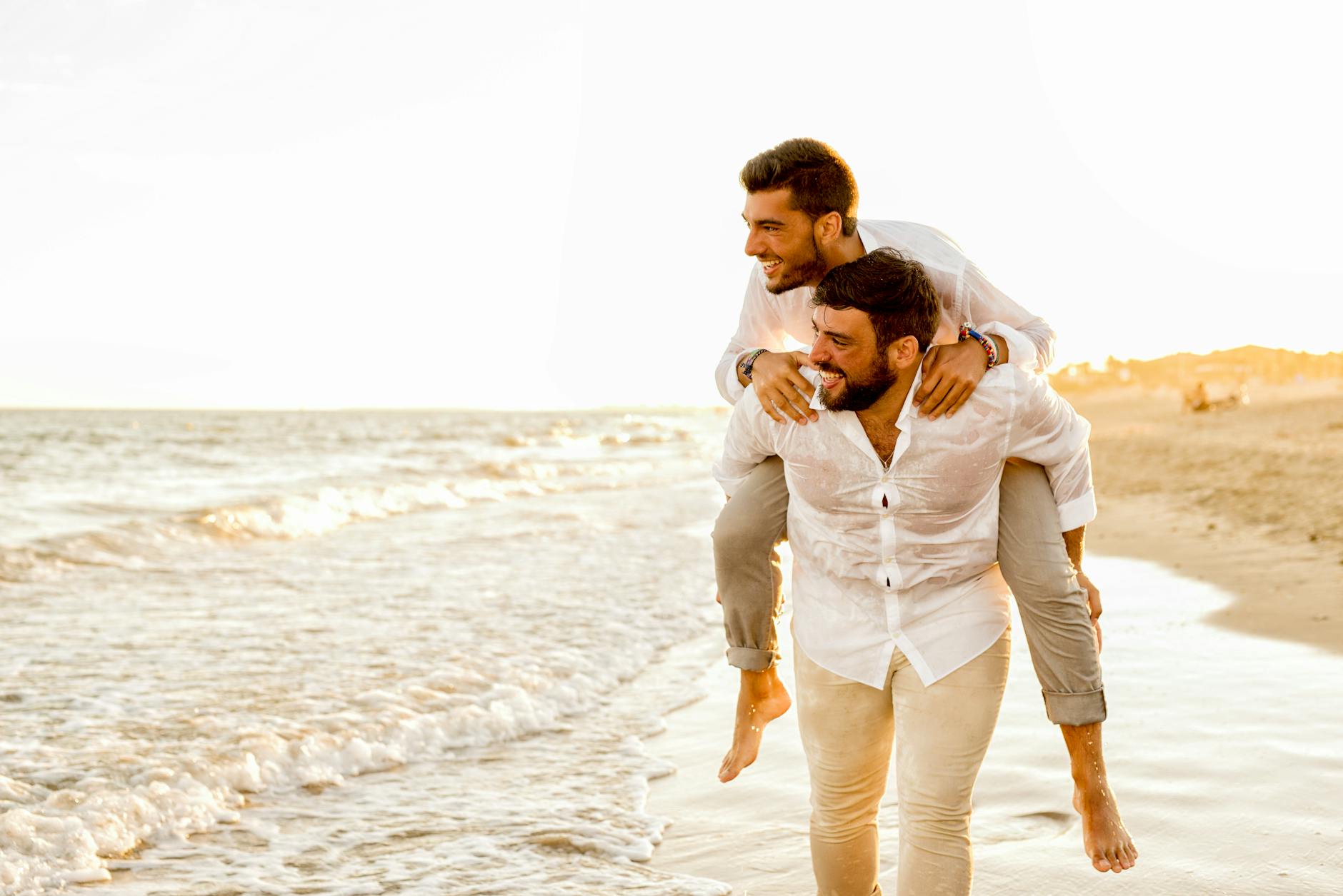 Two joyful men having fun on a beach in Almería, Spain, during a bright sunny day. - marriage advice men