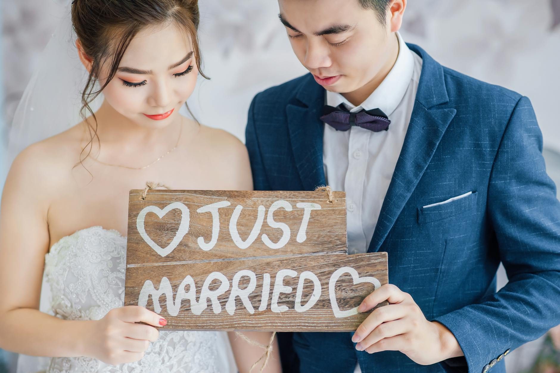 Newlywed couple in Vietnam holding a 'Just Married' sign, capturing a joyful moment. - marriage advice shower