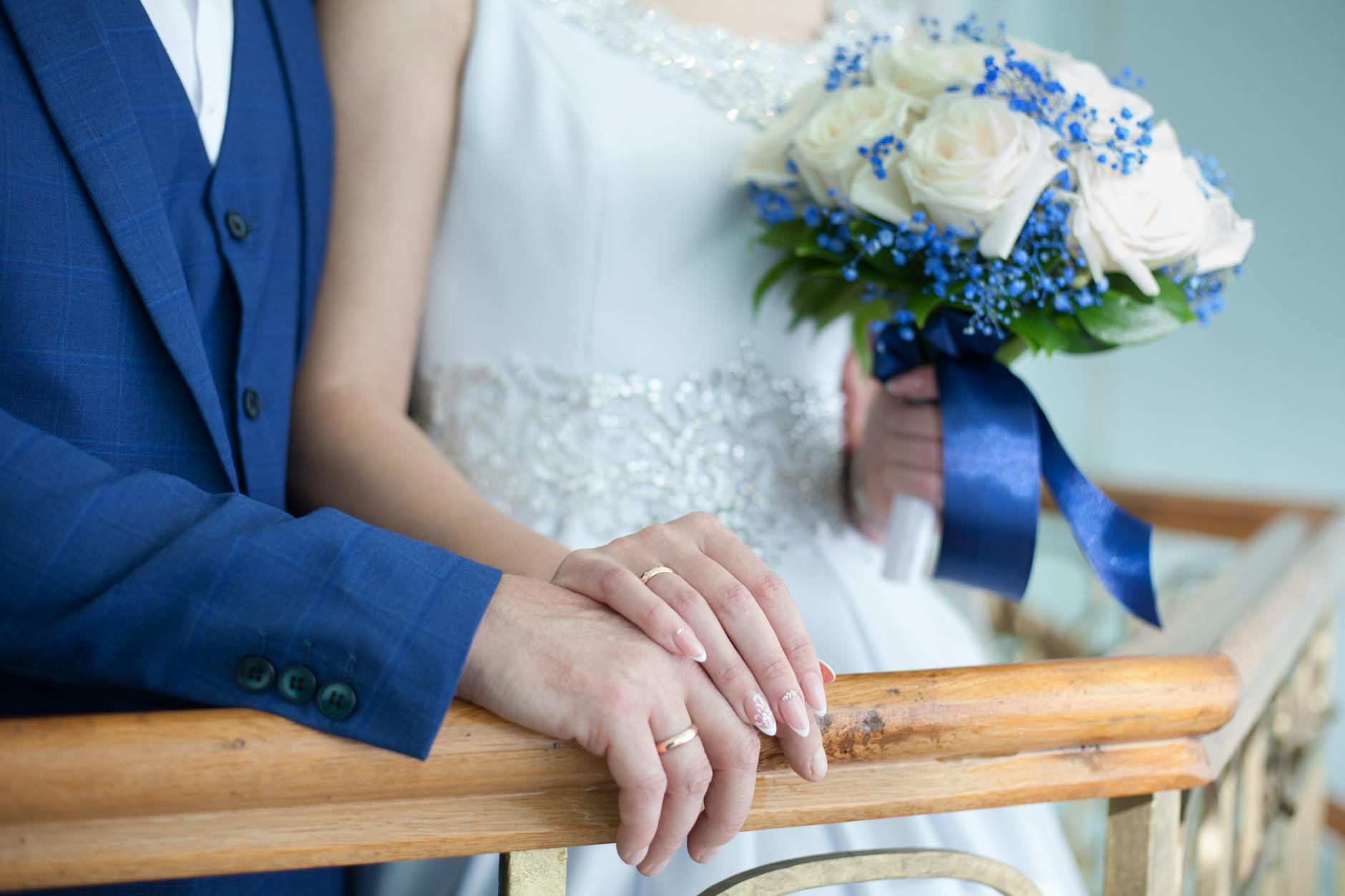 Bride and groom in elegant attire with bouquet and rings on wooden railing. - marriage advice shower