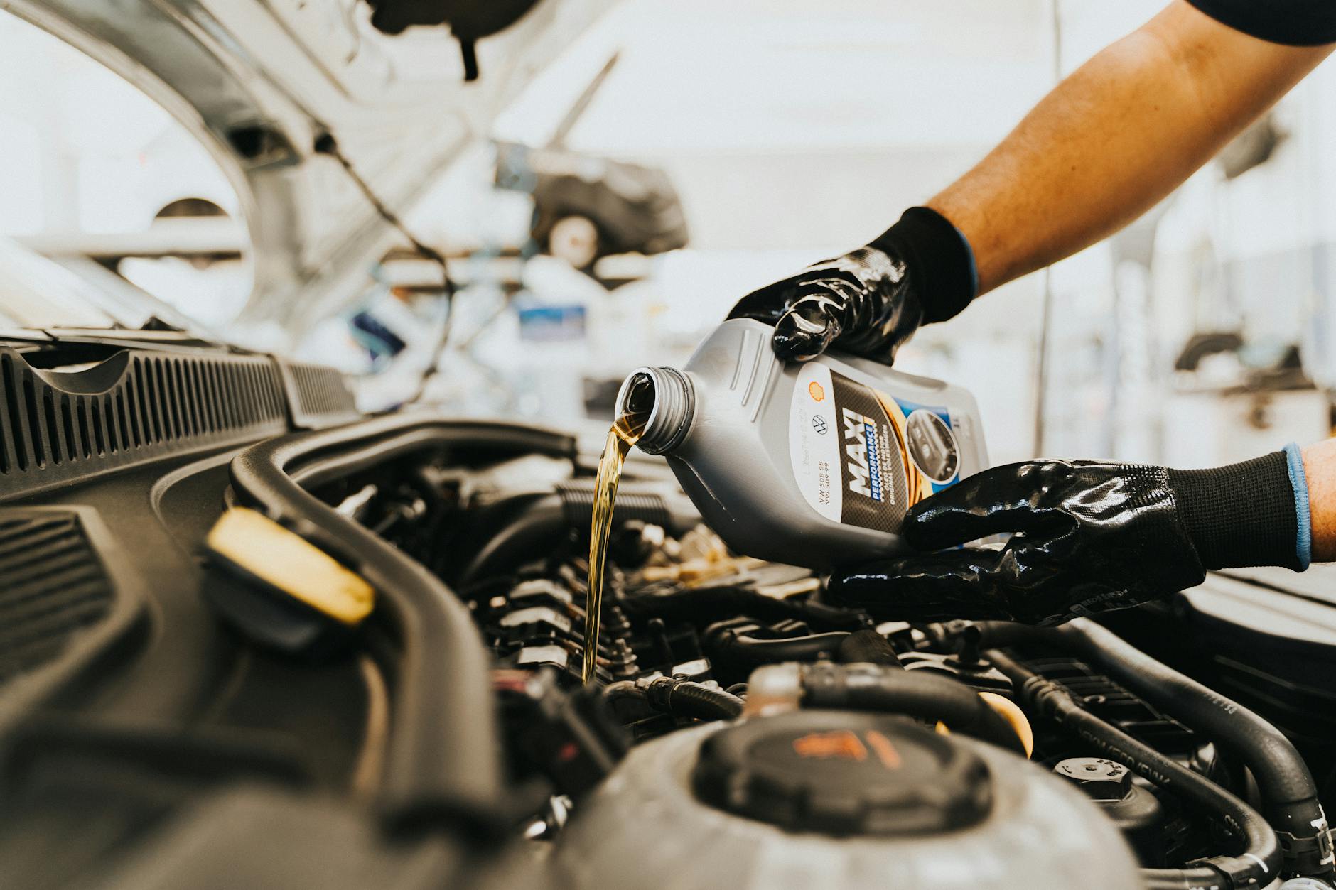 Close-up of a mechanic pouring engine oil into a car engine in an auto repair shop. - marriage maintenance tips
