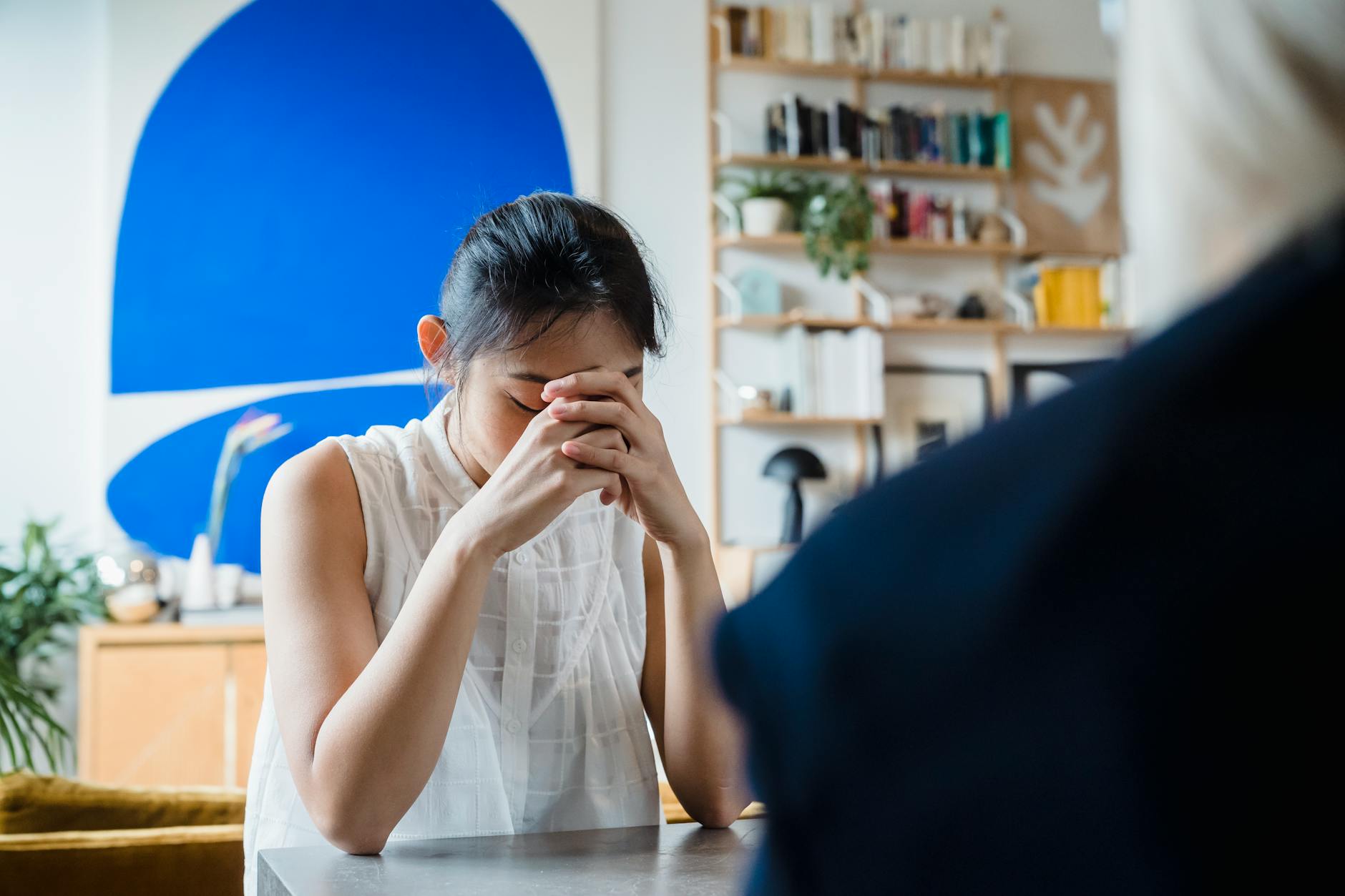 A woman appears deep in thought during an indoor therapy session. - midlife relationship counseling