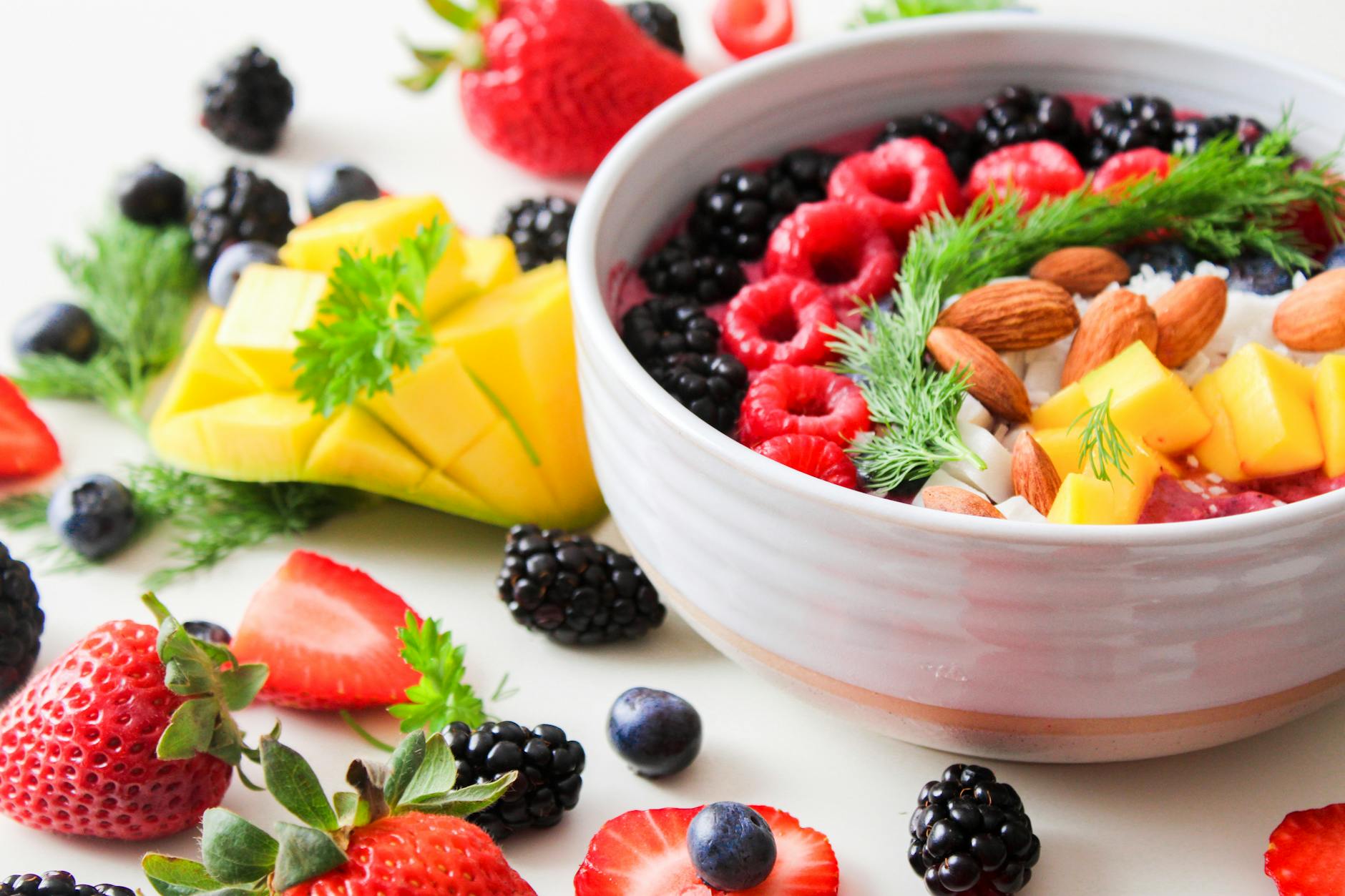 A vibrant bowl filled with fresh berries, mango, almonds, and herbs, perfect for a healthy snack or breakfast. - mindful eating winter wellness
