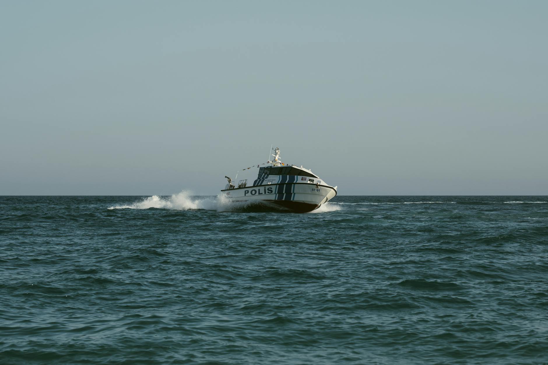 A police boat speeds across the open sea under clear skies, maintaining maritime security. - navigating spring break in-laws