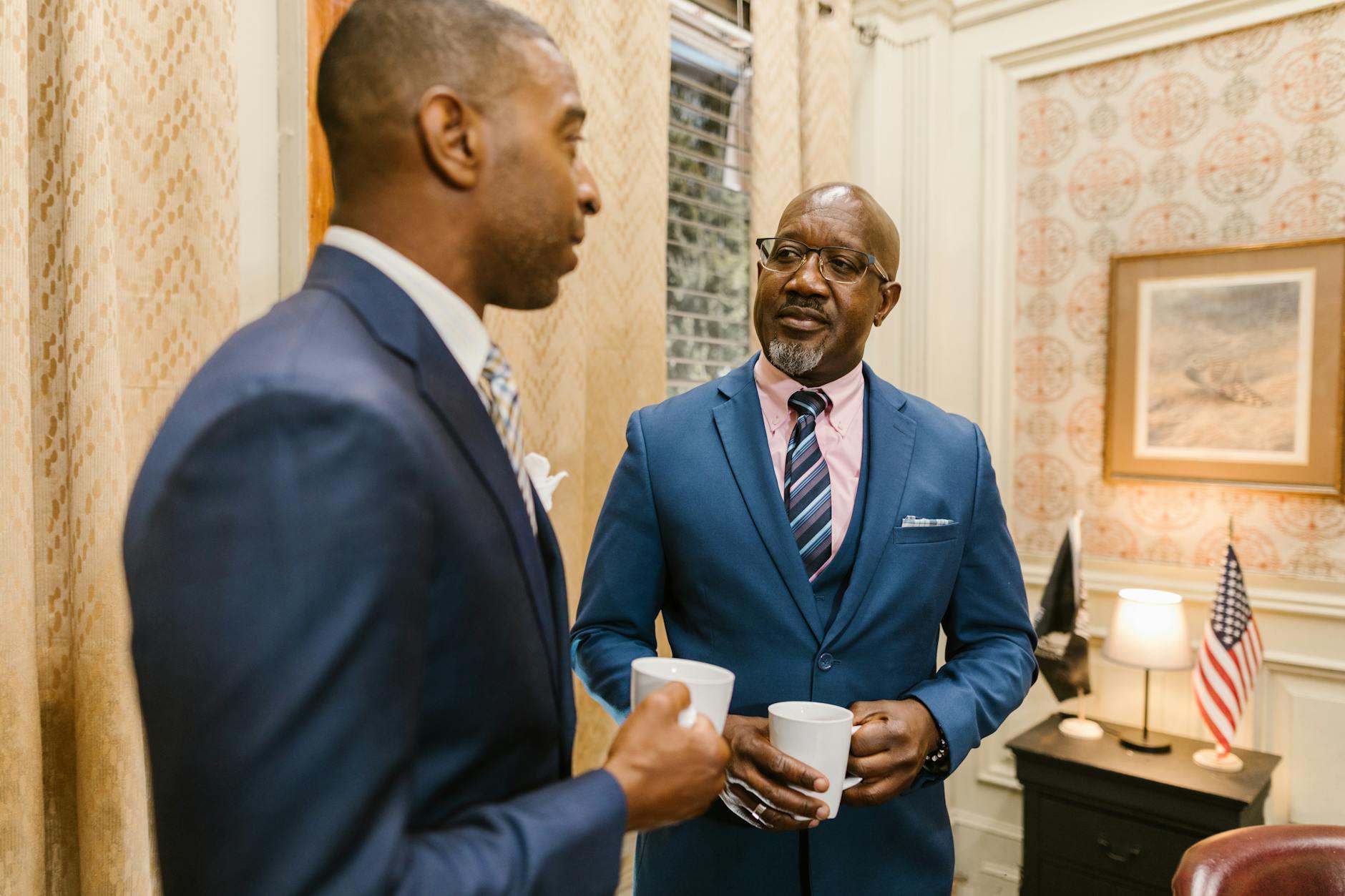 Two businessmen in suits having a coffee break and discussing business indoors. - navigating spring break in-laws