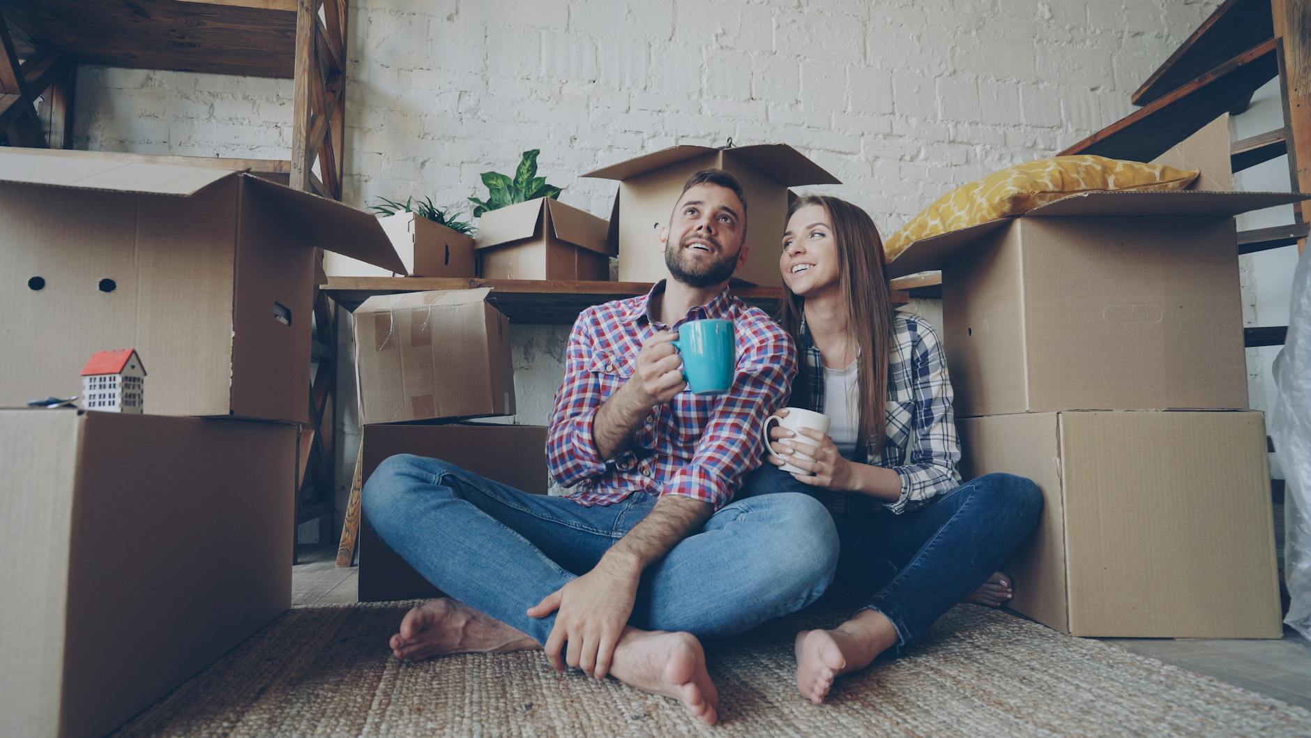 Couple enjoying coffee surrounded by moving boxes in their new home. - new relationship growth