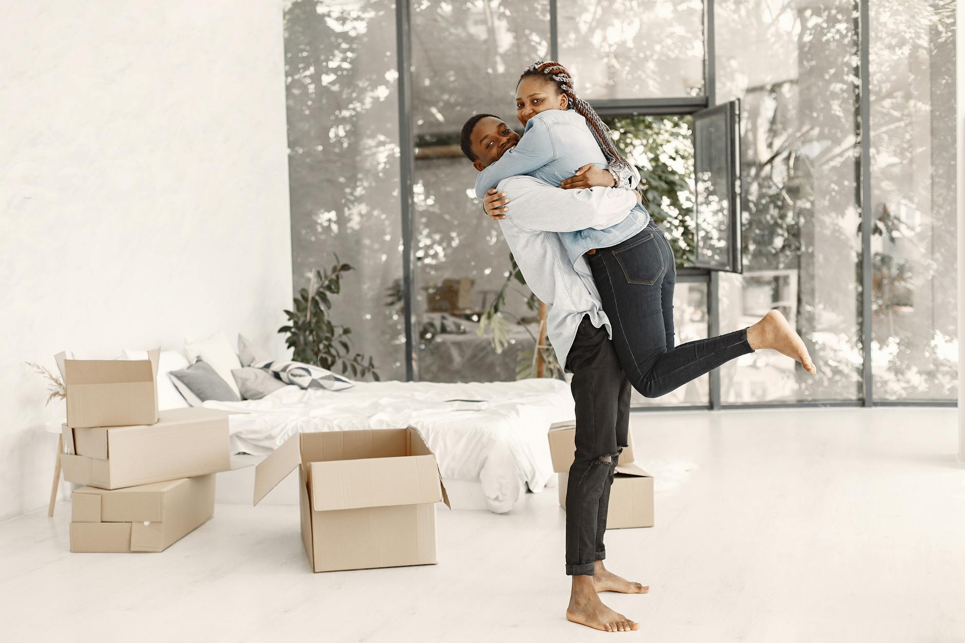 Joyful couple embracing in their new home surrounded by moving boxes, reflecting excitement and togetherness. - new relationship growth