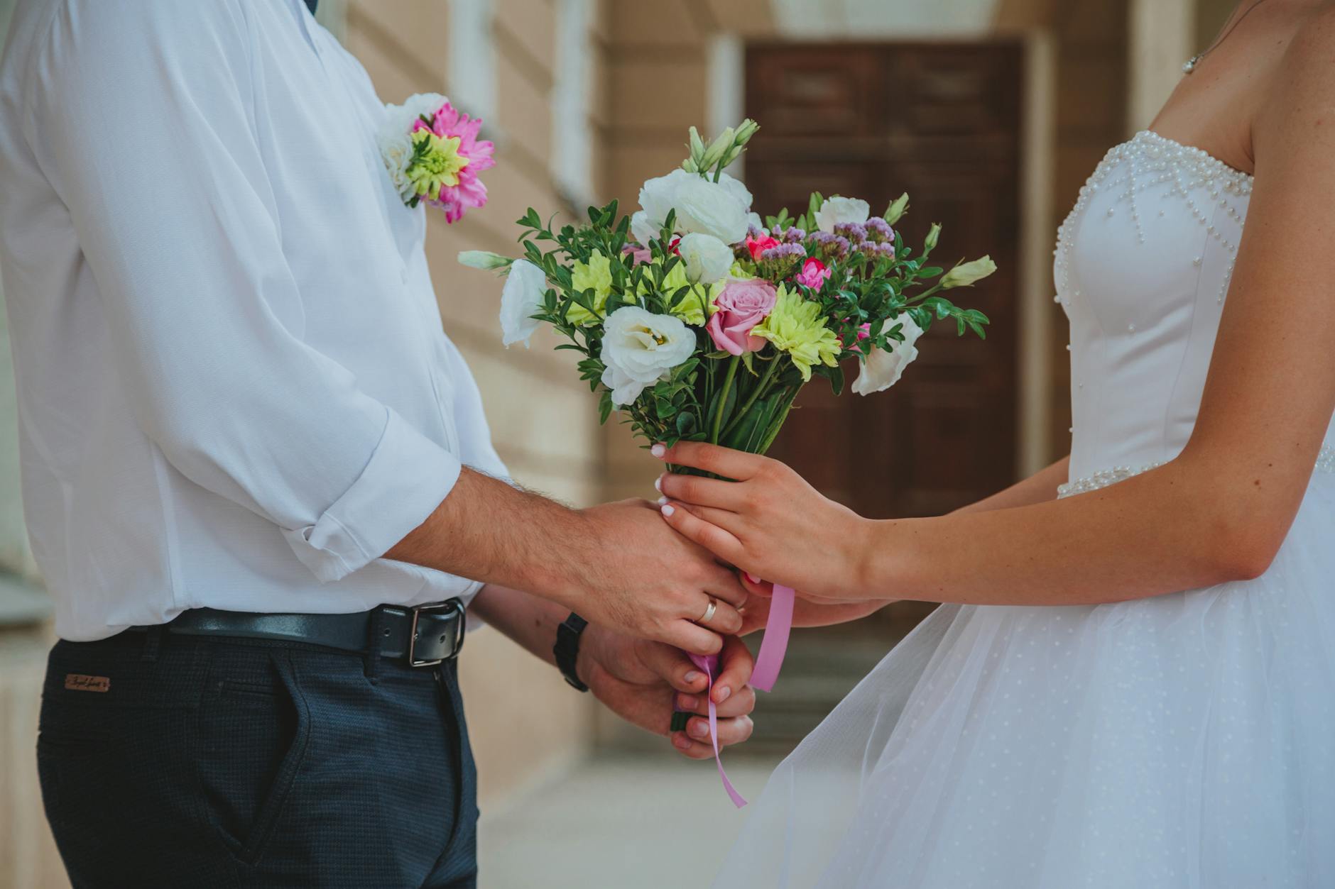 A newlywed couple holds a vibrant wedding bouquet, symbolizing love and union. - newlywed marriage advice