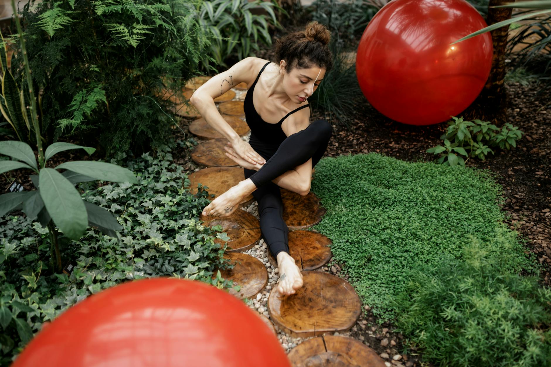 Woman practicing yoga amidst nature with exercise balls in a tropical garden setting. - outdoor play benefits