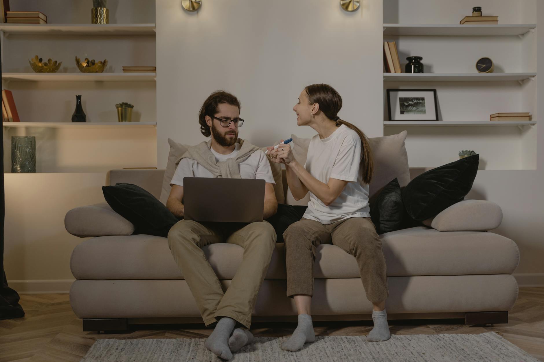 Happy couple sitting on couch, celebrating pregnancy news with test results. - partner needs communication
