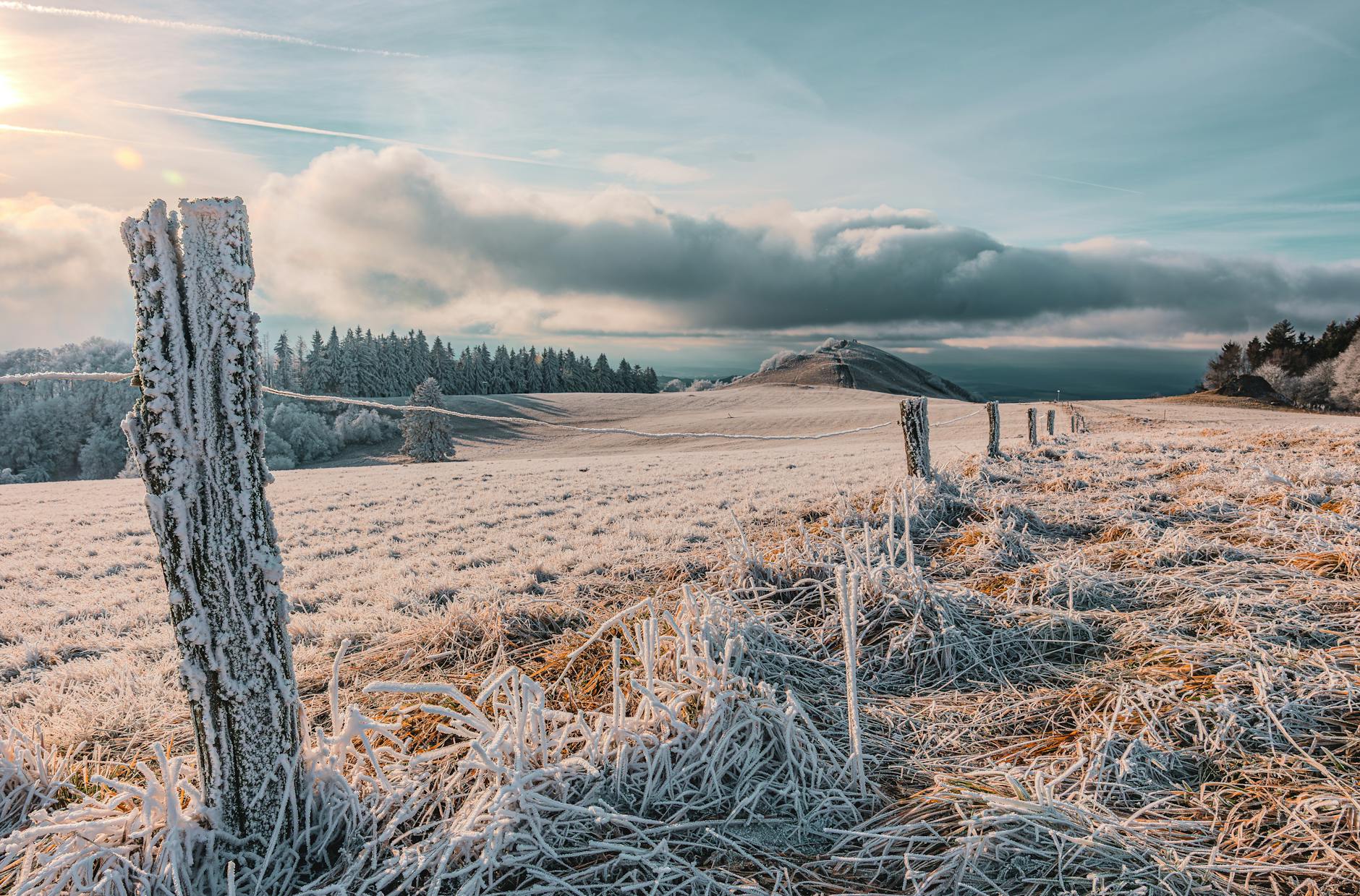 A serene winter landscape showing frost-covered fields at sunrise with a distant hill and cloudy sky. - post-hibernation conversations