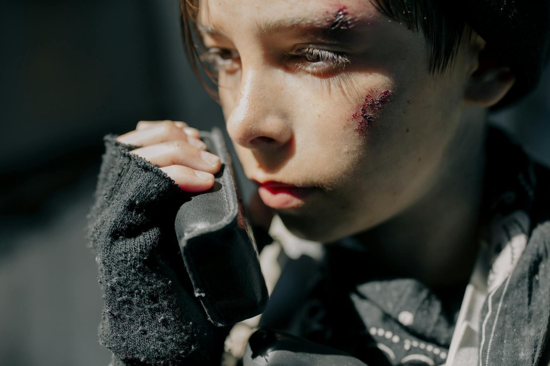 Close-up portrait of a young boy with wounds, using a radio, conveying a survival theme in a post-apocalyptic setting. - post holiday relationship challenges