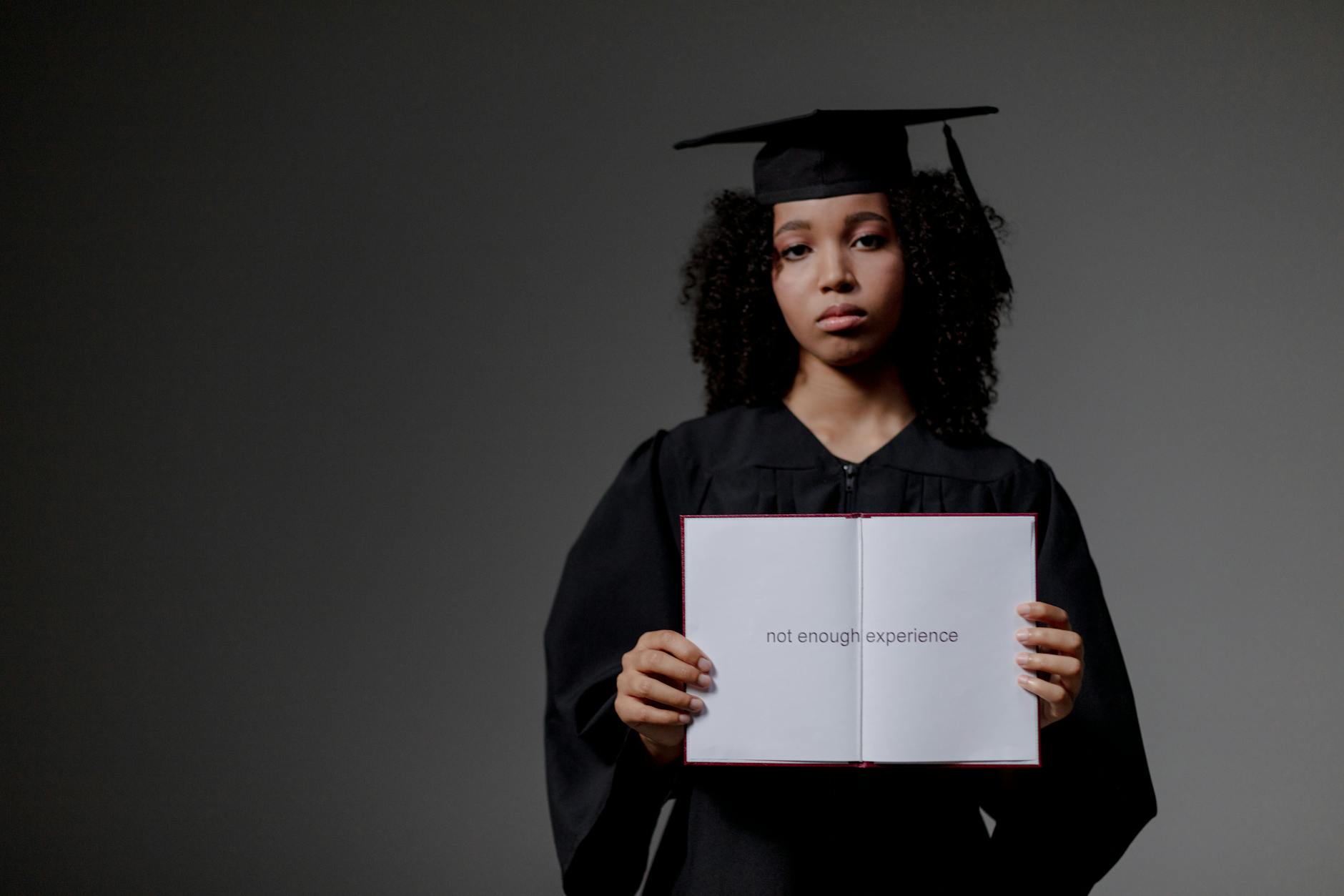 Young graduate holding a book with 'not enough experience' message, symbolizing job hunt difficulties. - post holiday relationship challenges