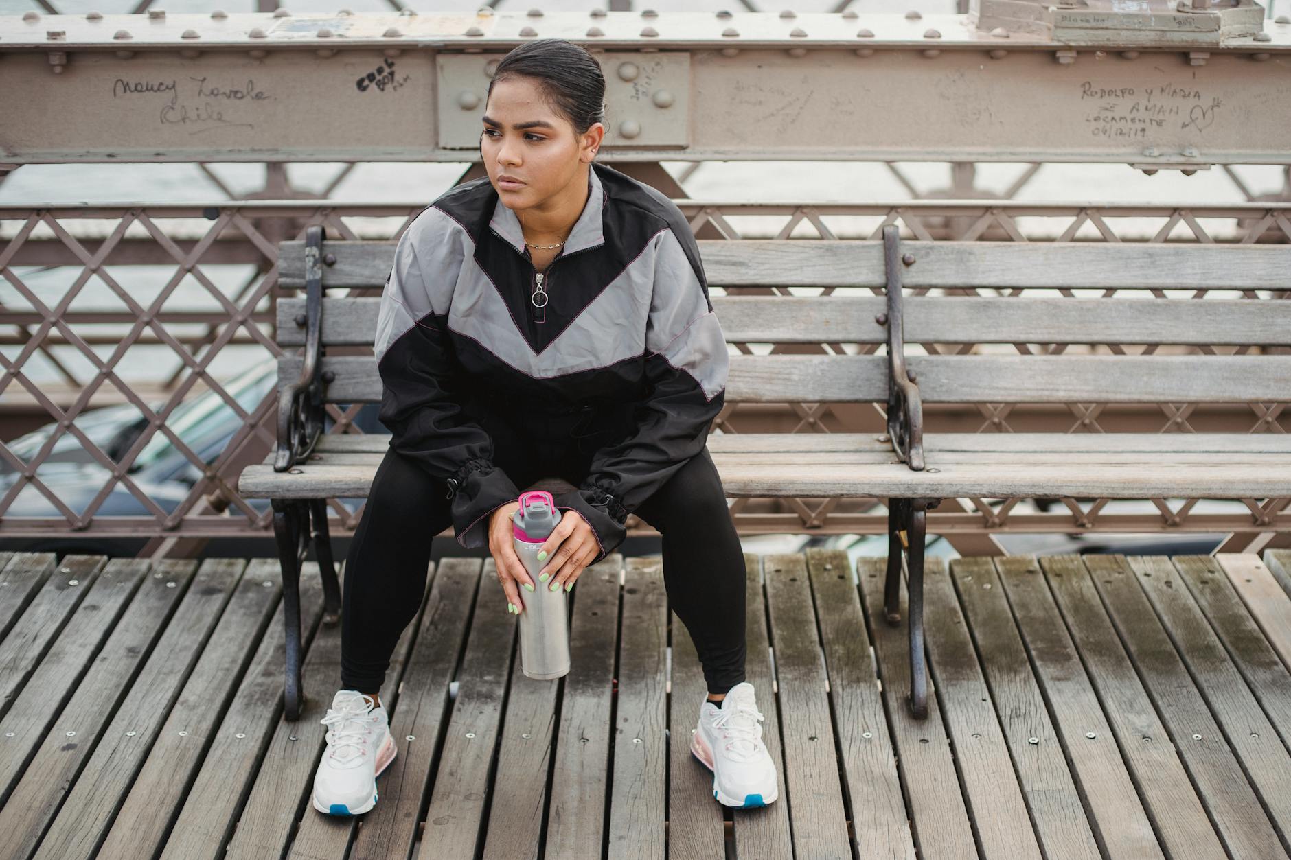 Woman sitting on a bench, taking a break from jogging with a water bottle in hand. - post winter break routine
