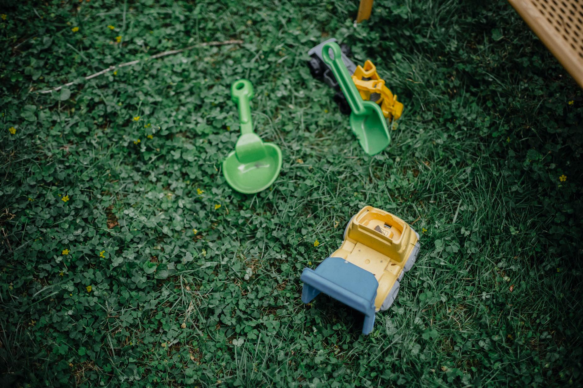 High angle of green grass and colourful plastic kids toys on garden meadow - preschool outdoor learning