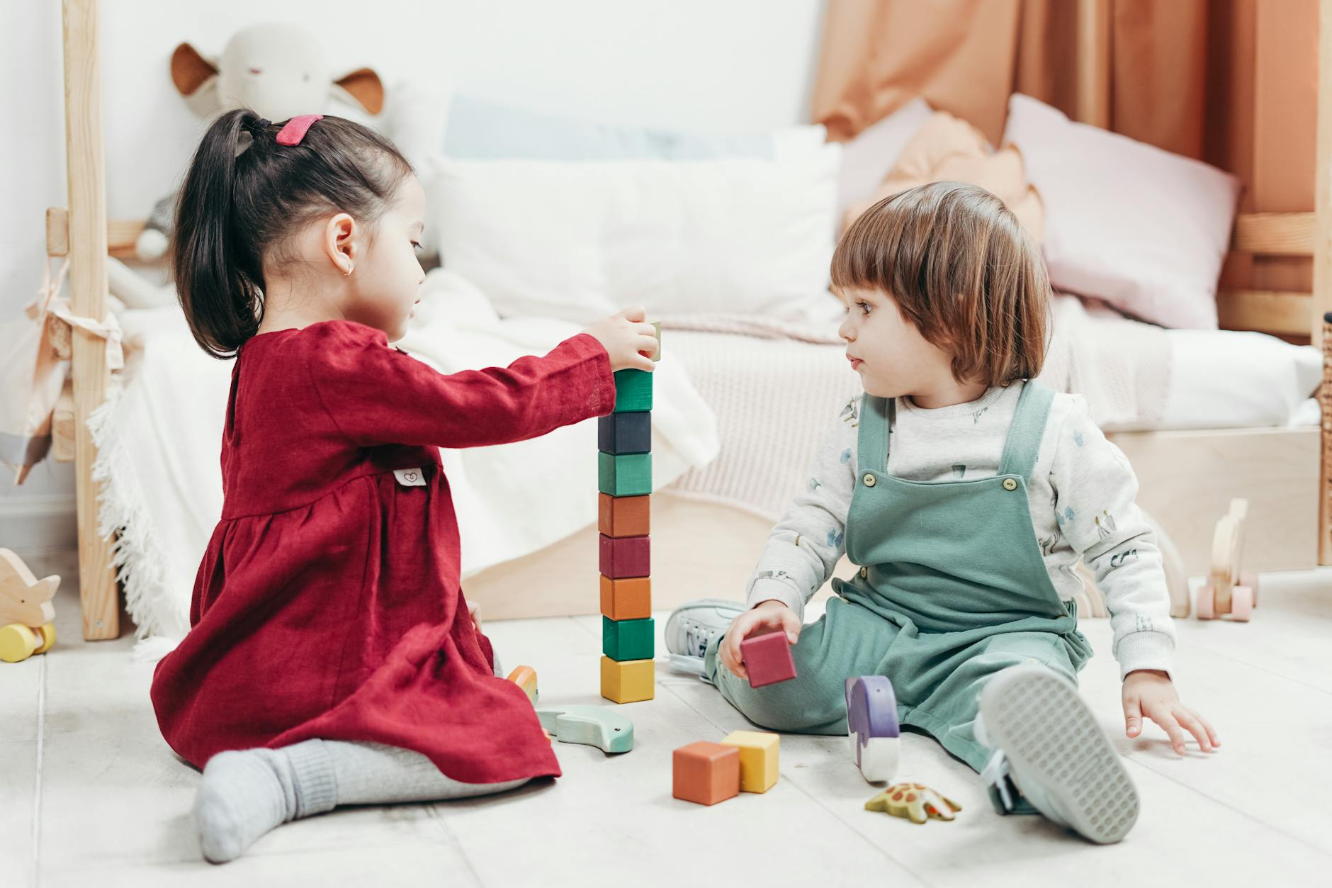 Two children happily playing together with colorful wooden blocks, indoors. - preschool social skills