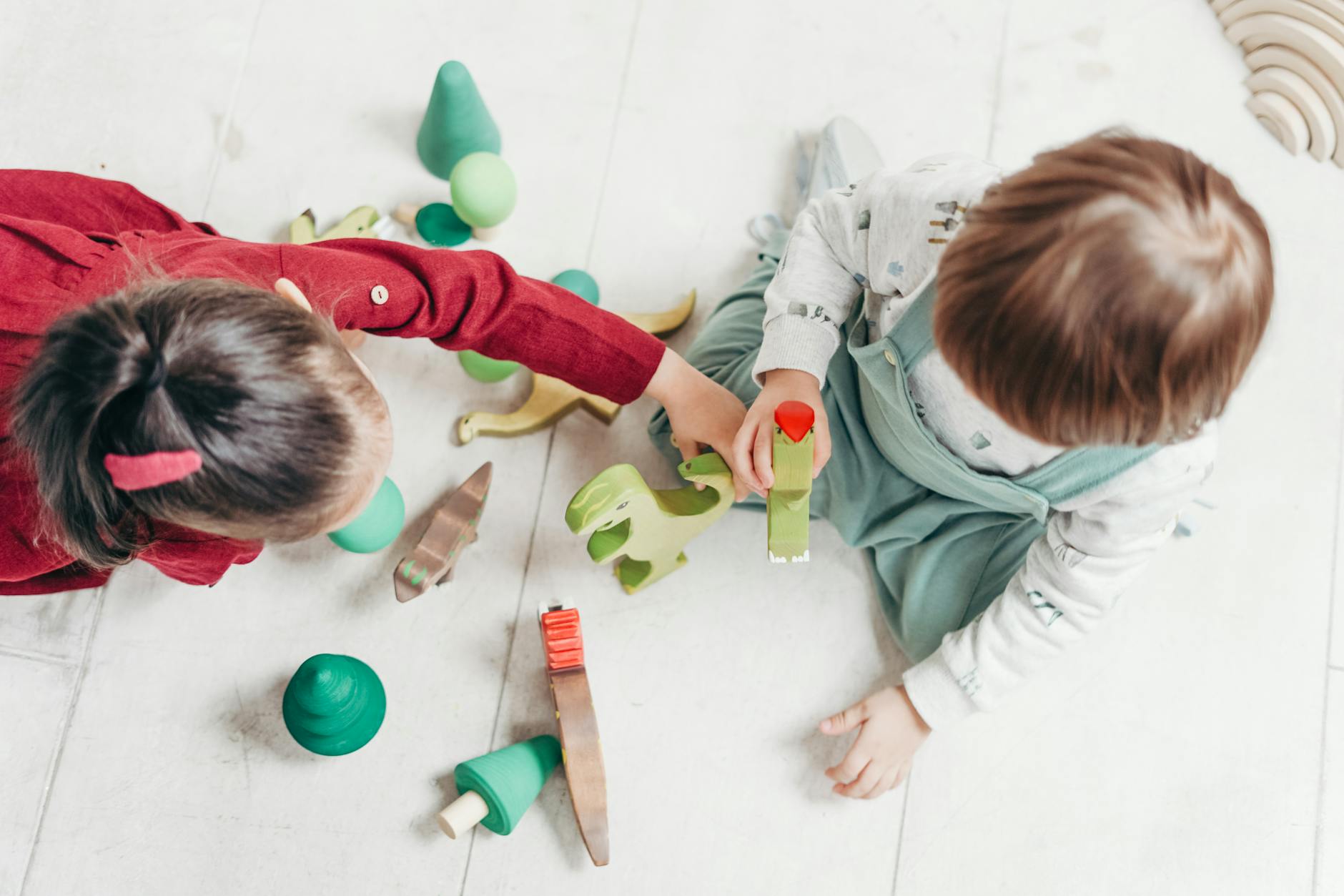 Two young children playing with colorful wooden toys indoors, promoting creativity and fun. - preschooler independence