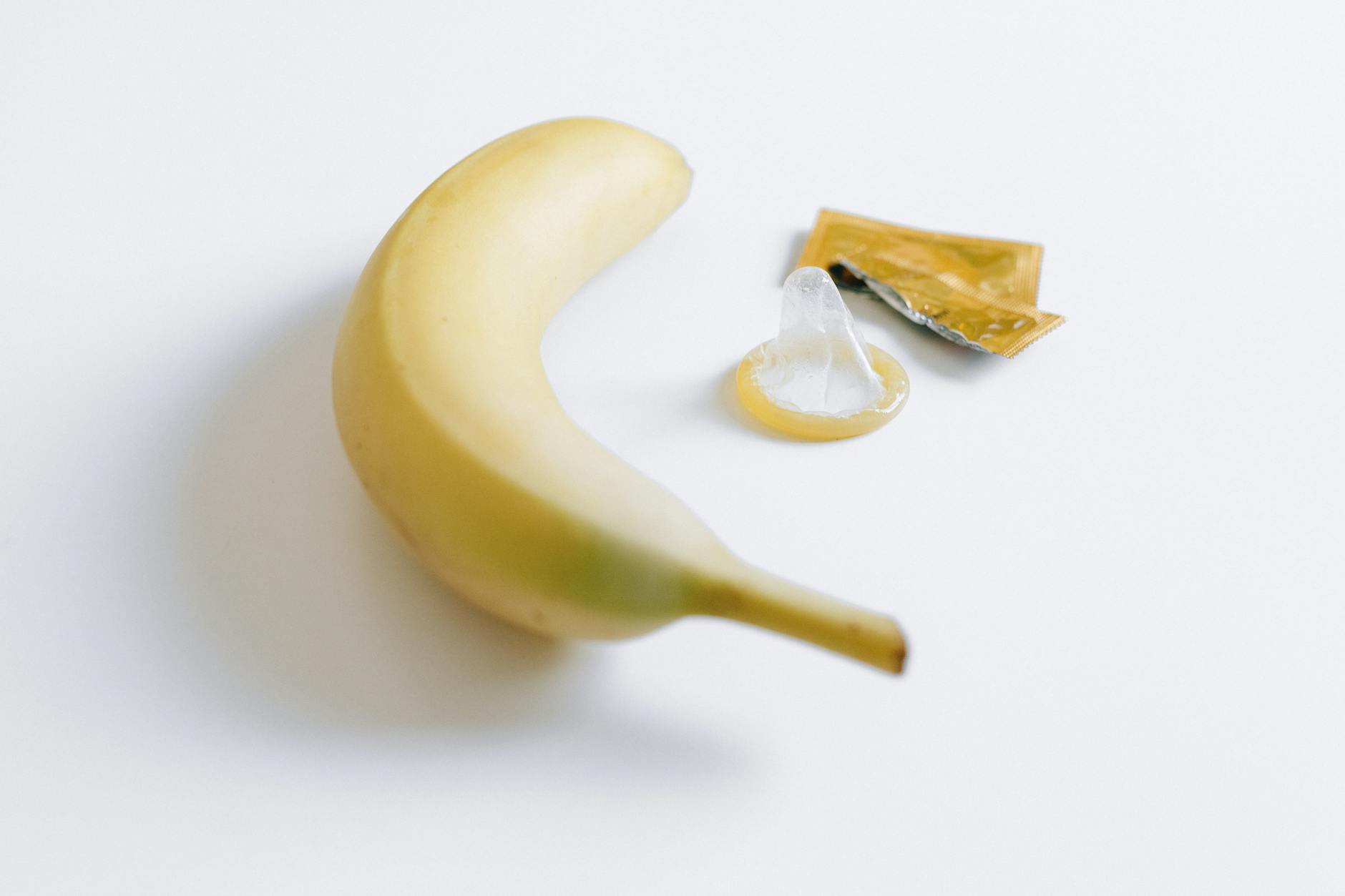 Conceptual image featuring a banana and a condom on a white background, symbolizing safe sex education. - prevent spring s.a.d.