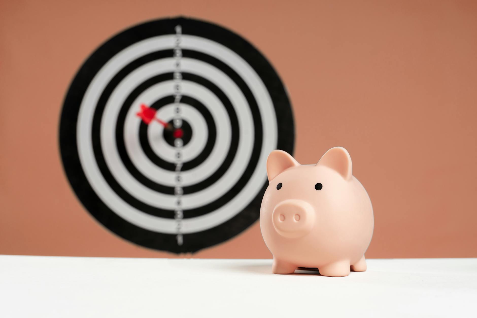 A piggy bank in front of a dartboard symbolizing financial goals and smart savings. - realistic personal growth goals