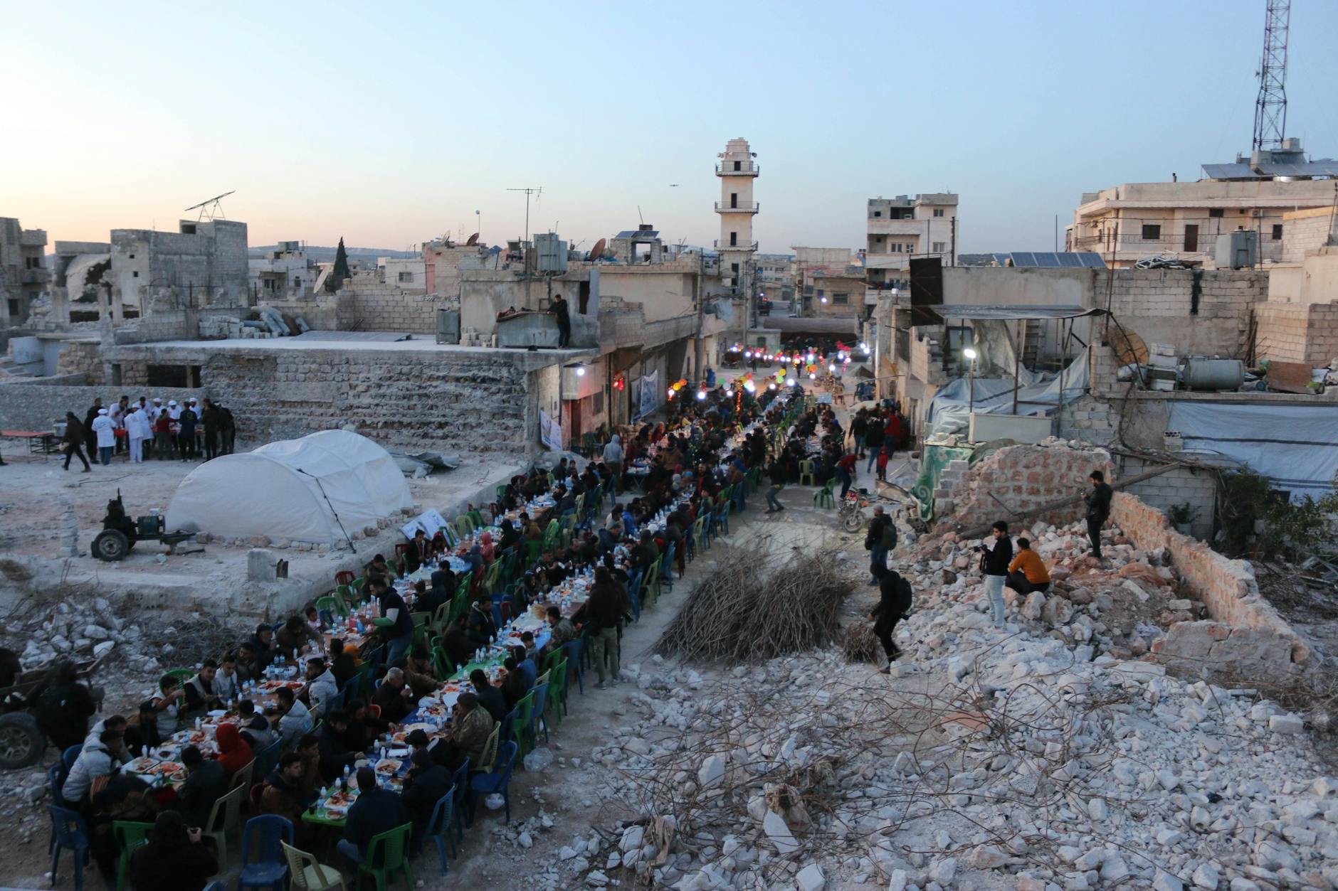 Large group dining in war-torn Idlib, Syria. Community gathered for a shared meal in outdoor urban rubble. - rebuild trust infidelity