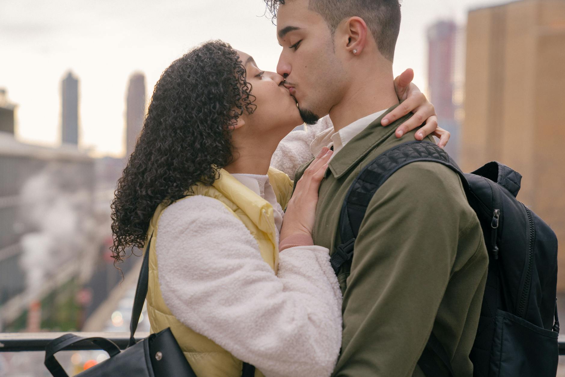 Side view of crop ethnic boyfriend kissing young girlfriend on blurred background of town - rebuilding trust couples