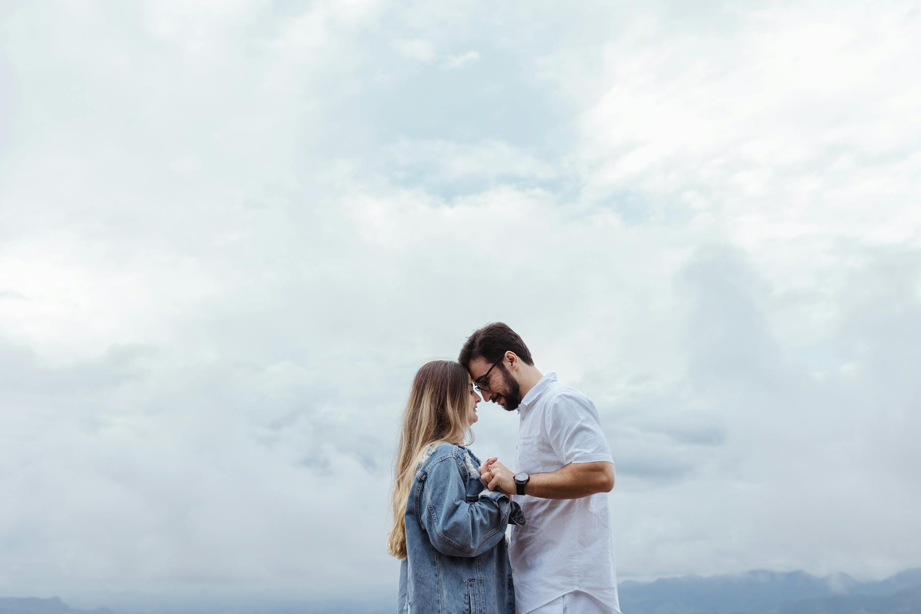 A couple standing close together under a cloudy sky, signifying love and connection. - rebuilding trust couples