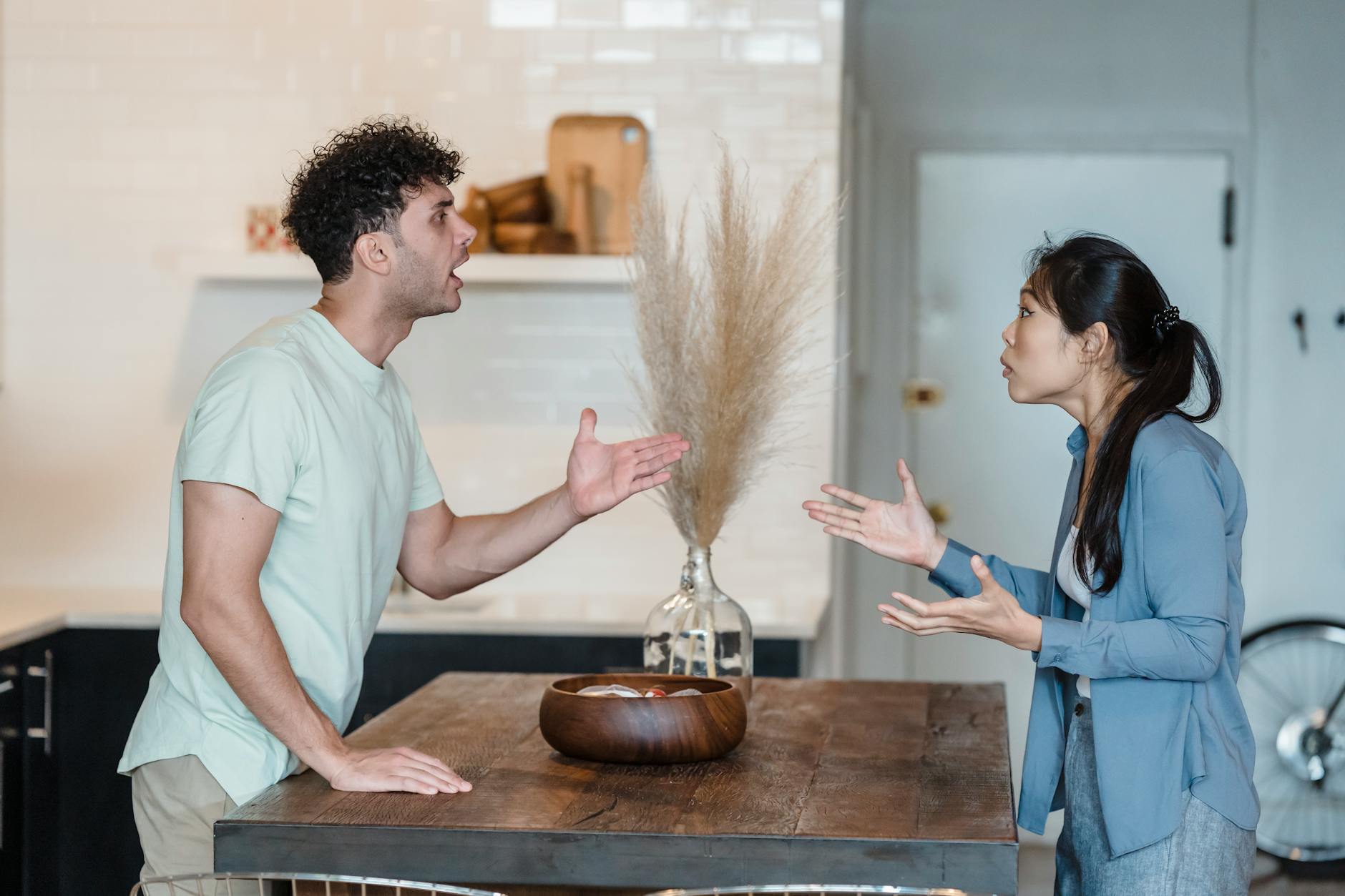 A couple engages in a heated argument at a wooden table in a modern indoor setting. - reconnecting with partner