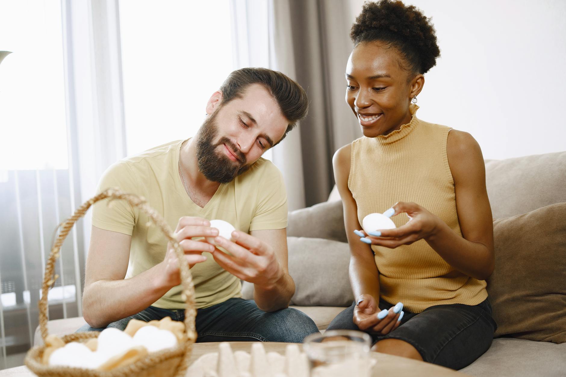 Happy diverse couple decorating Easter eggs together in a cozy indoor setting. - reddit marriage advice