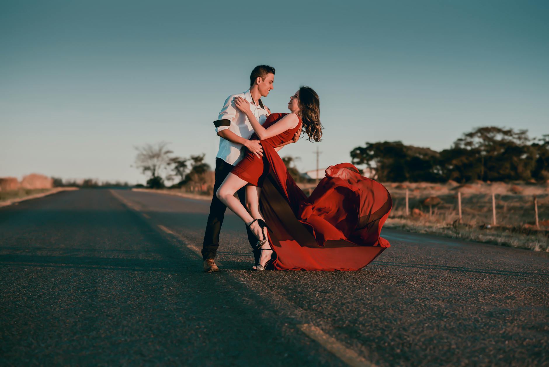 A couple in a passionate dance pose on an empty highway at sunset, showcasing love and romance. - reignite passion relationship
