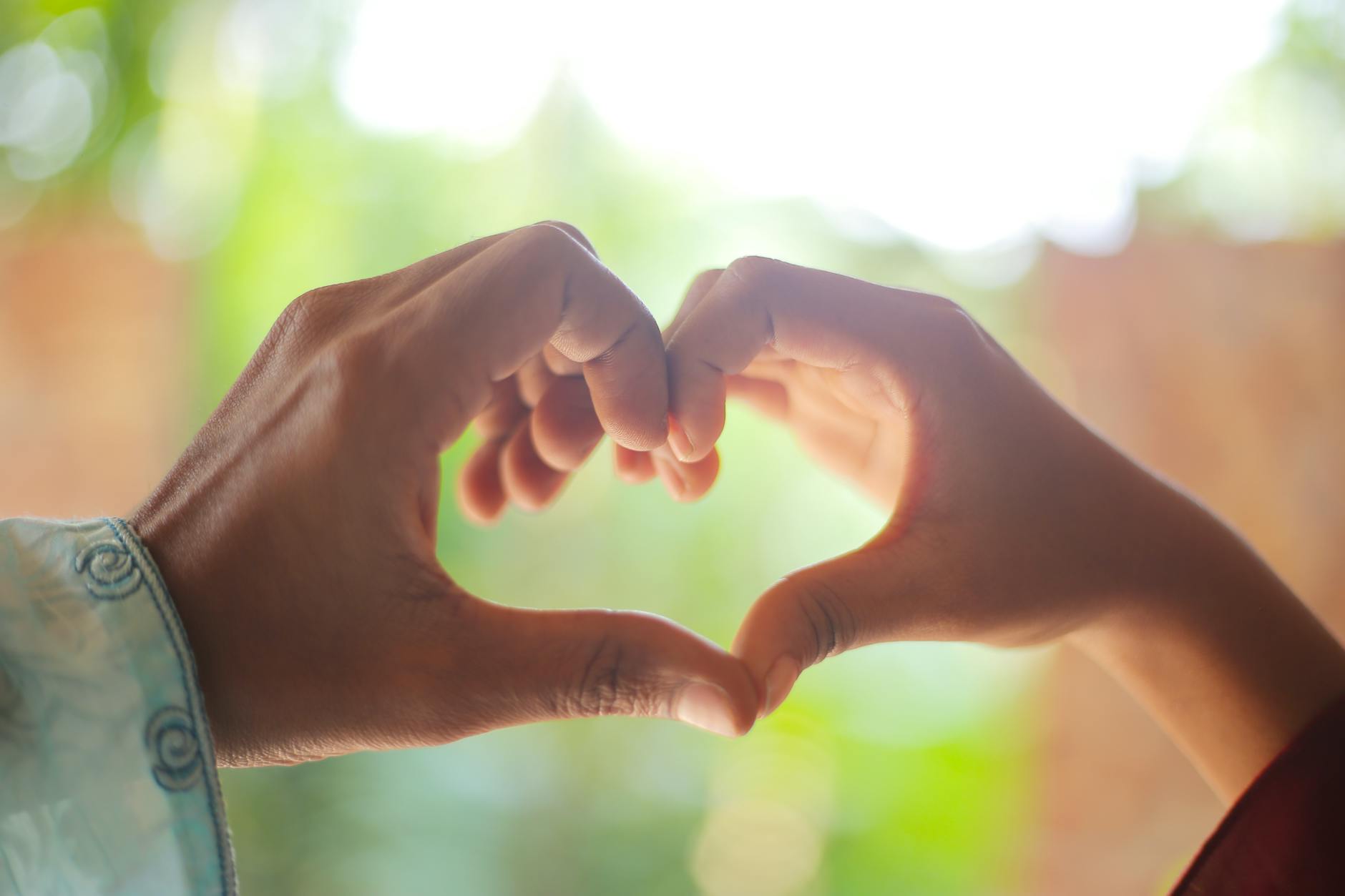 A close-up of two hands forming a heart shape outdoors, symbolizing love and connection. - rekindle relationship connection