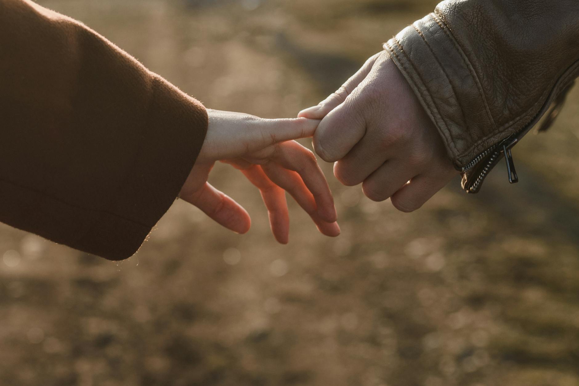 Close-up of two hands connecting, symbolizing love and connection in a warm setting. - rekindle relationship connection