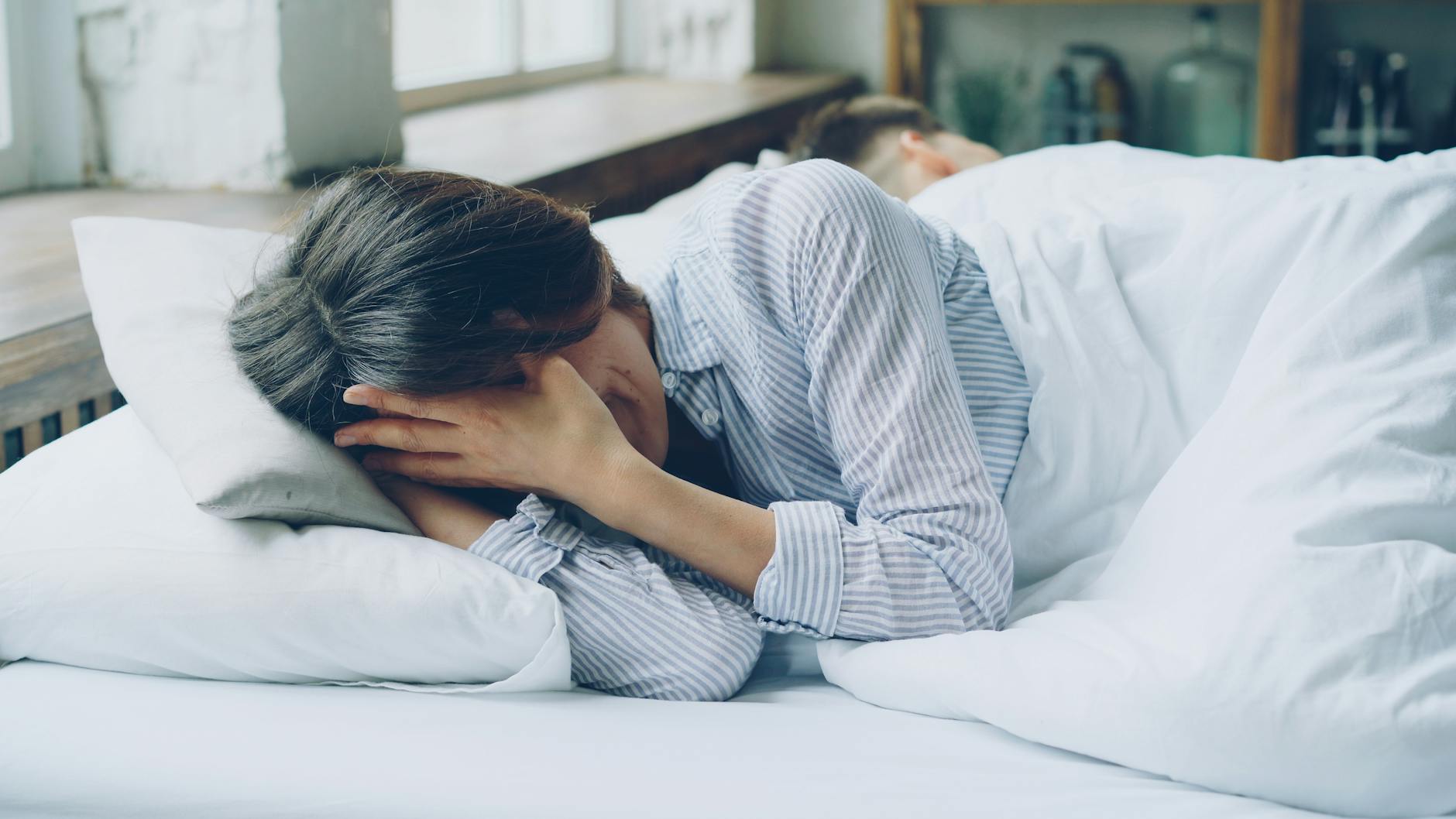 A woman in bed showing signs of anxiety. Soft light indoors. - relationship anxiety reddit