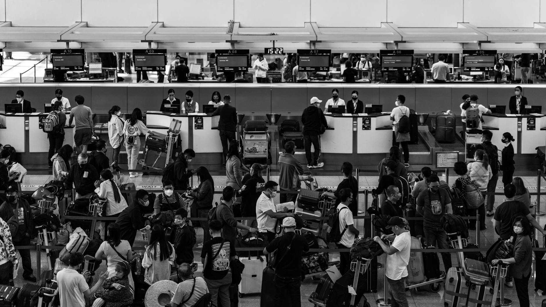 Black and white photo capturing a crowded airport check-in area filled with passengers and staff. - relationship communication check-in