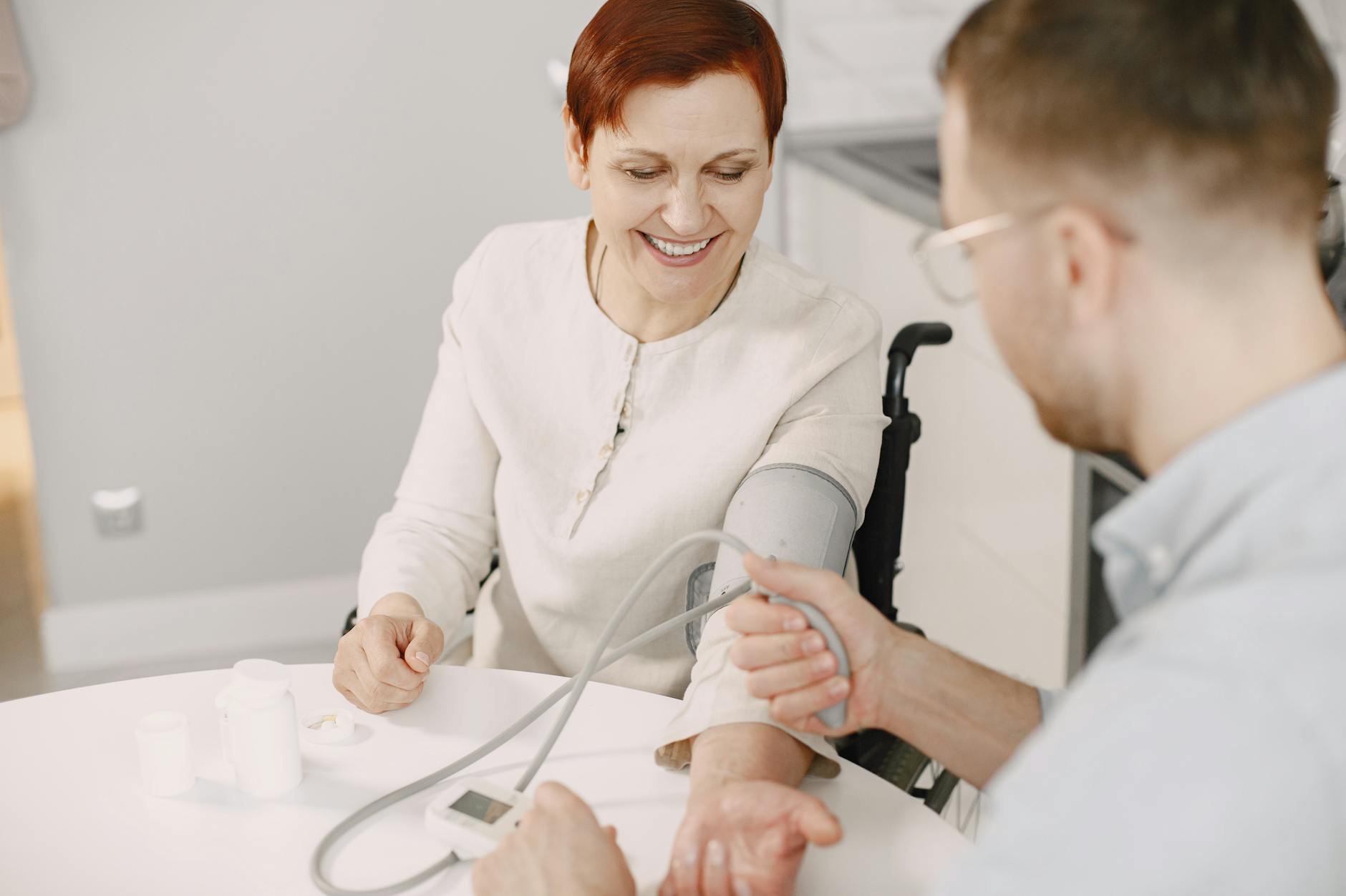 Man assisting elderly woman with blood pressure check at home in a friendly atmosphere. - relationship communication check-in