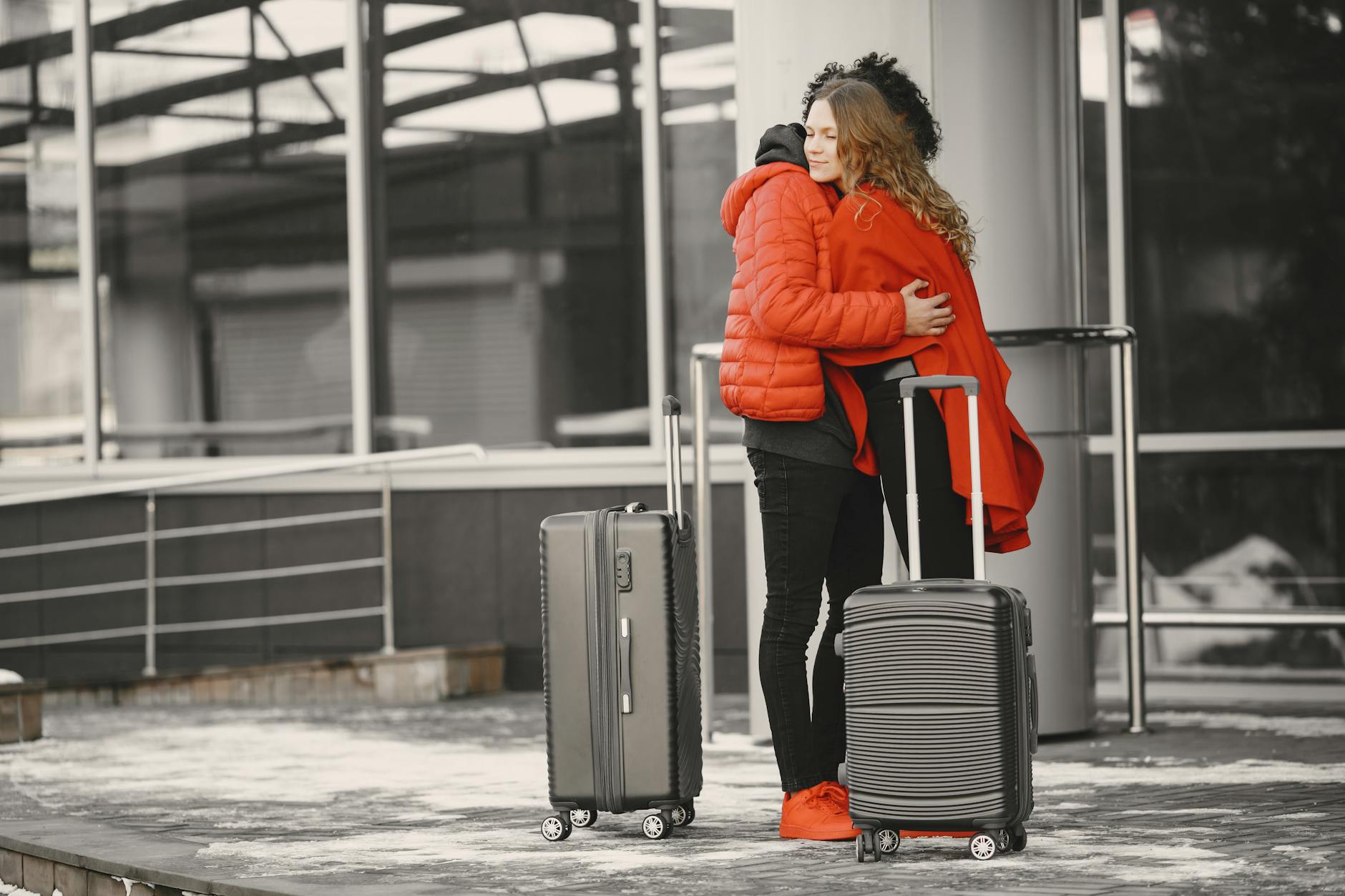 A heartfelt goodbye at the airport with two people hugging and luggage present. - relationship emotional baggage