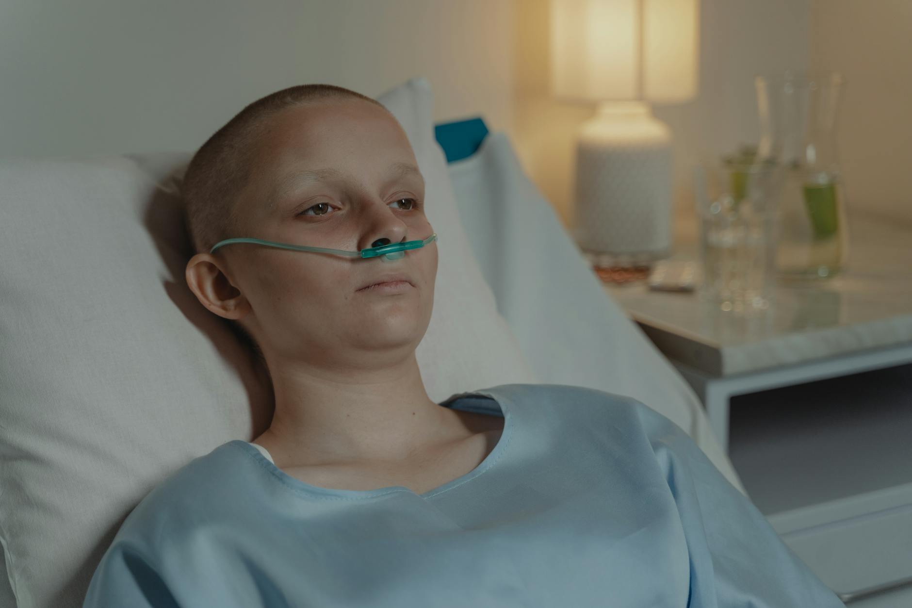 A woman in a hospital bed wearing an oxygen tube, expressing a calm yet serious demeanor. - sad cbt treatment