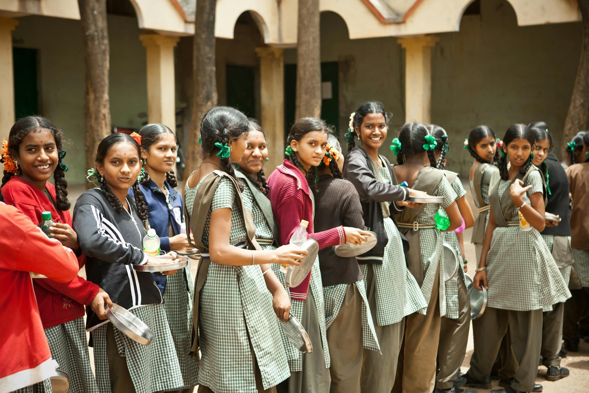 Group of smiling schoolgirls with braids standing outdoors during lunchtime at school. - school break transition