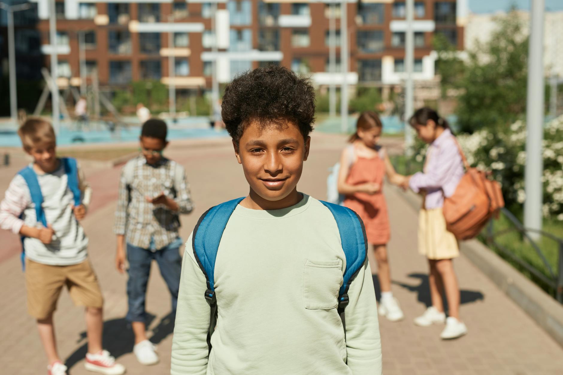 Group of children happily returning to school on a sunny day, carrying backpacks and smiling. - school closure activities