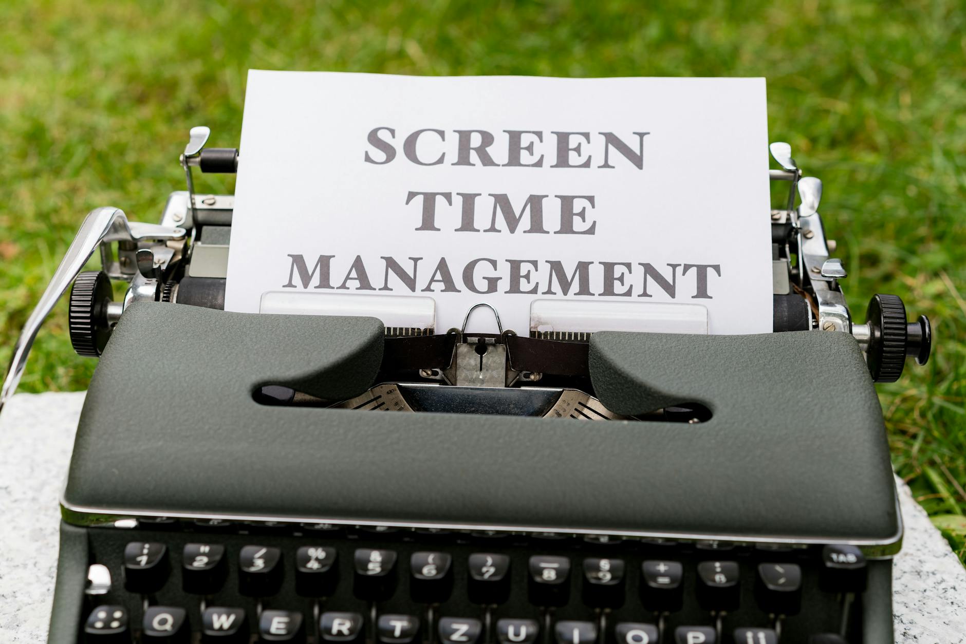 Retro typewriter displaying 'Screen Time Management' on paper outdoors. - screen time balance