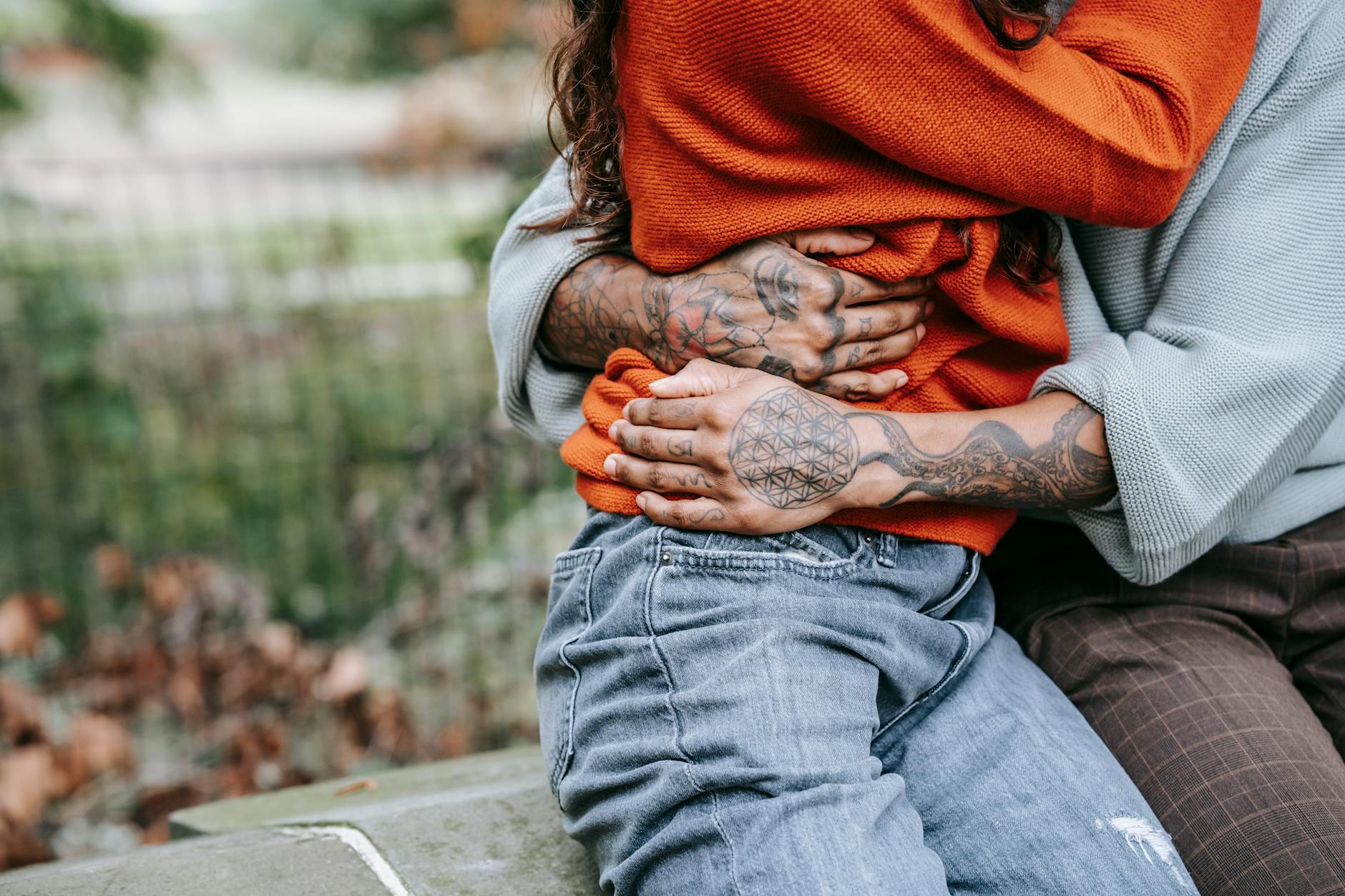 A tattooed couple embraces warmly in a park setting, showcasing love and connection. - secure attachment style