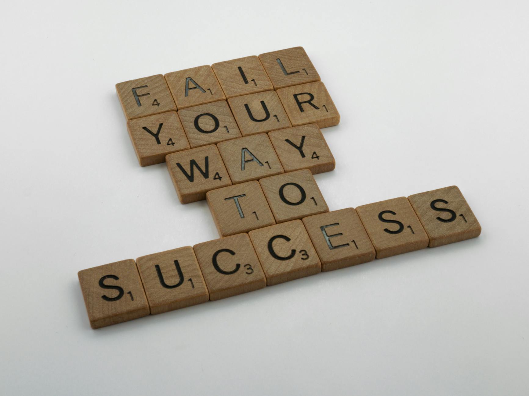 Wooden tiles spell 'Fail Your Way to Success' emphasizing perseverance. - self-compassion after failed resolutions