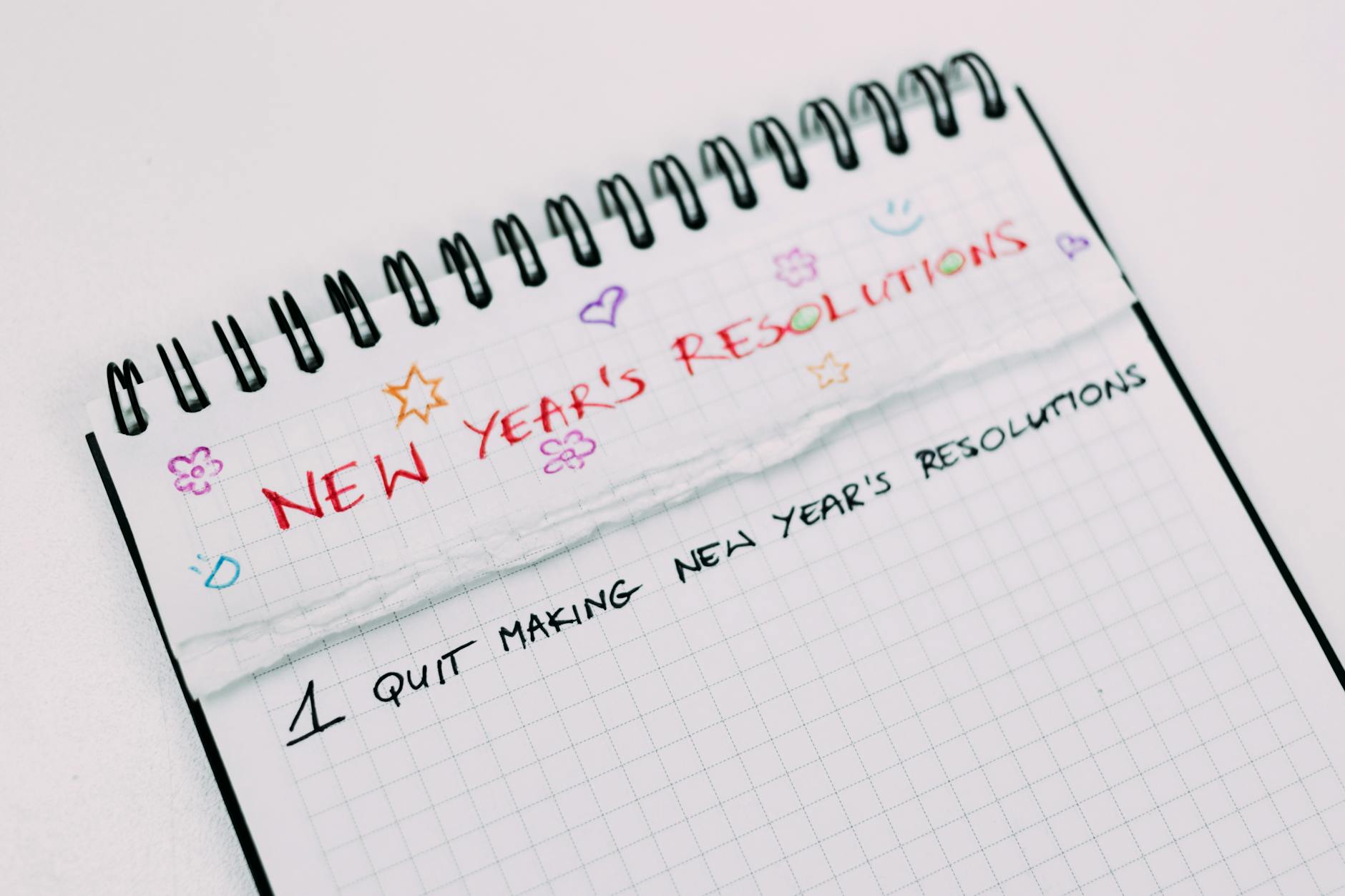 A notebook page with handwritten New Year's resolutions in colorful text. - self-compassion after failed resolutions