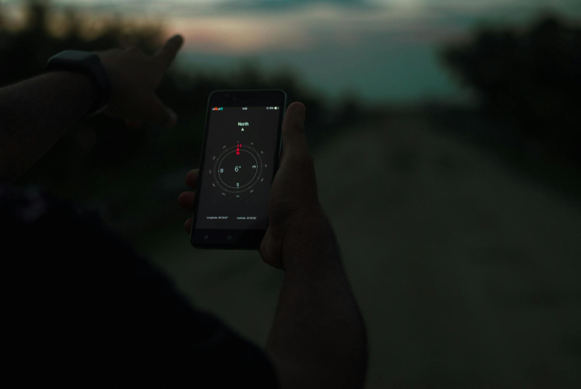 Person navigating using a smartphone compass app outdoors at twilight. - self-compassion guide