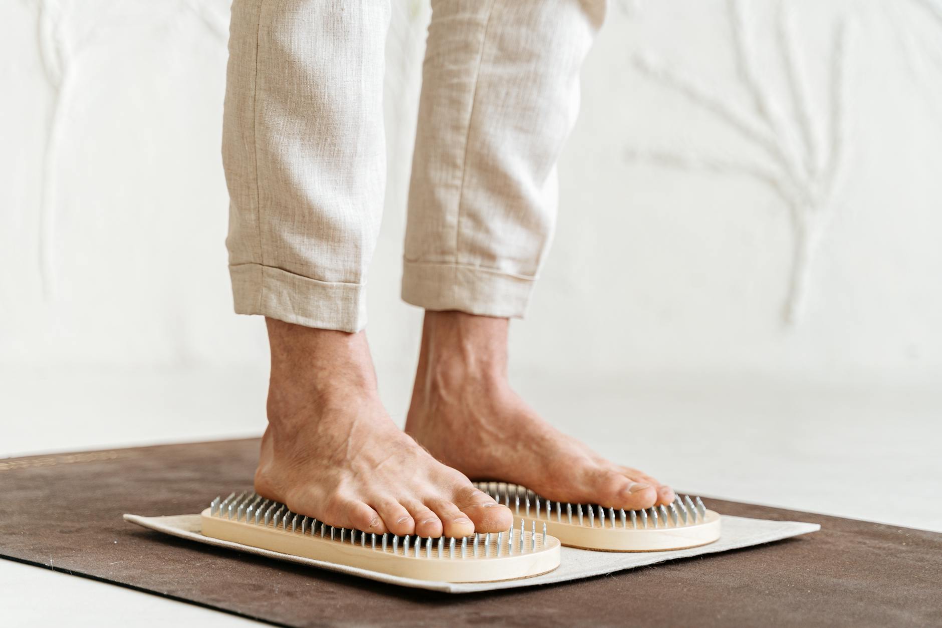 Close-up of an adult's feet practicing acupressure with a Sadhu board indoors. - self-compassion practices