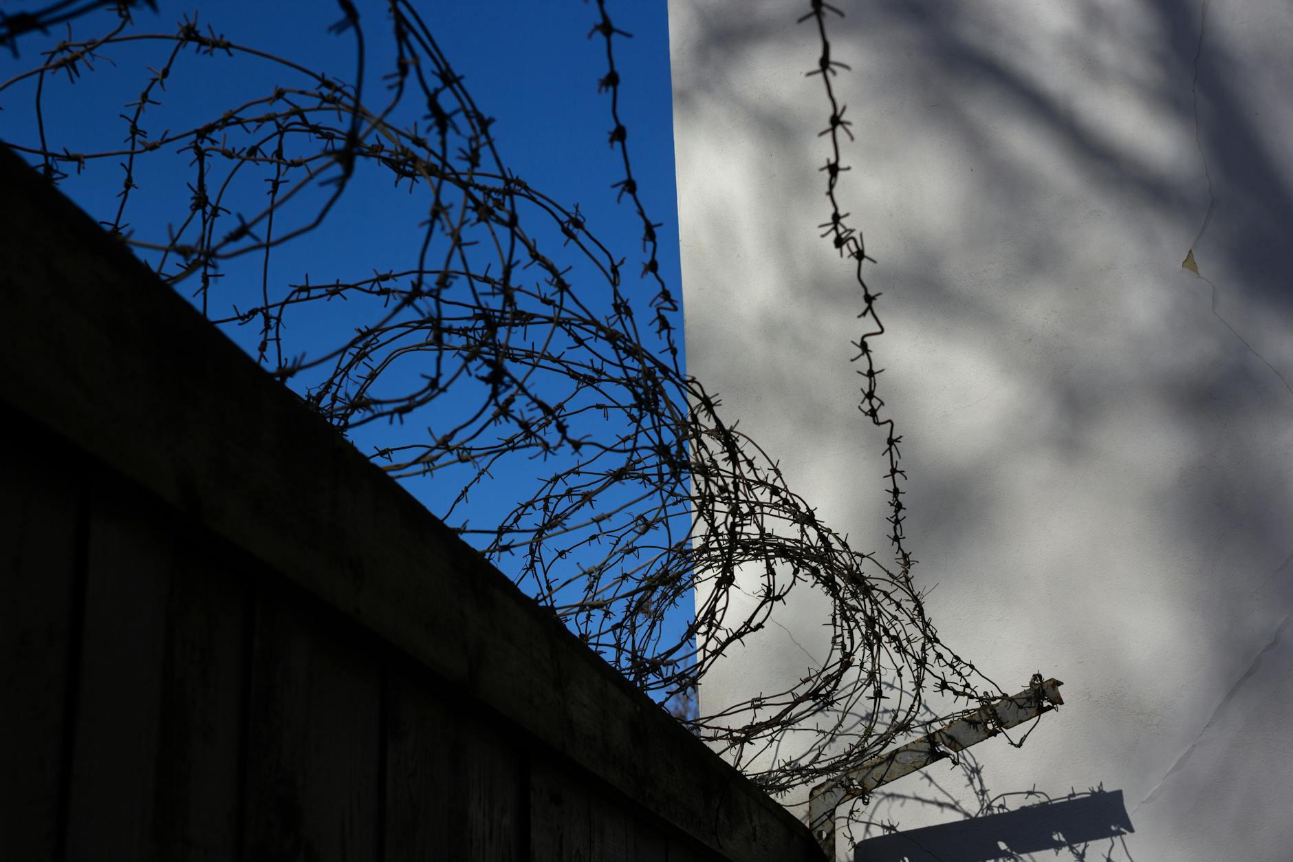 Barbed wire atop a concrete fence casting shadows, symbolizing security and restriction. - setting boundaries after isolation