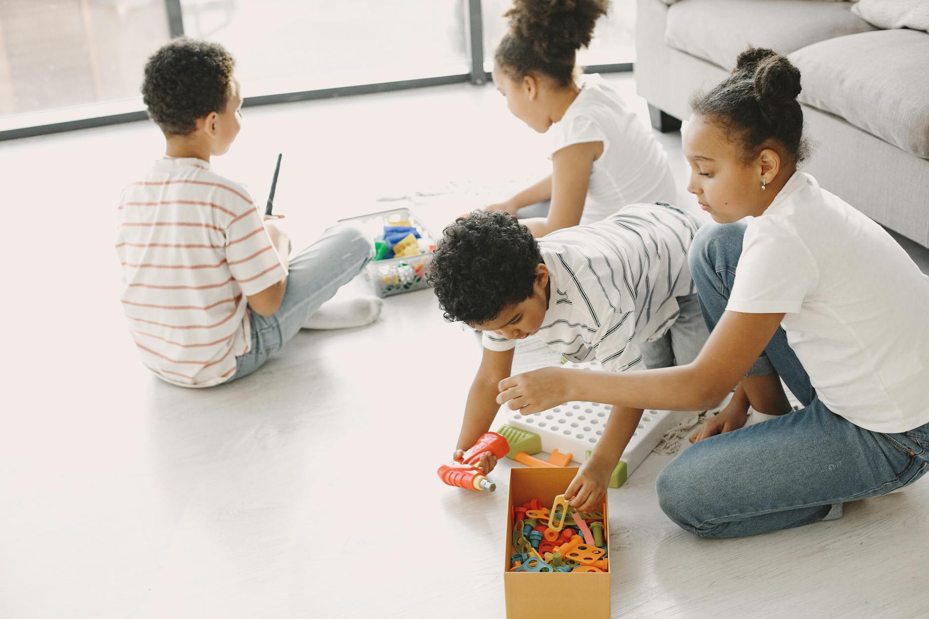 Four children engaged in creative play with toys on the living room floor, fostering imagination and teamwork. - social skills activities