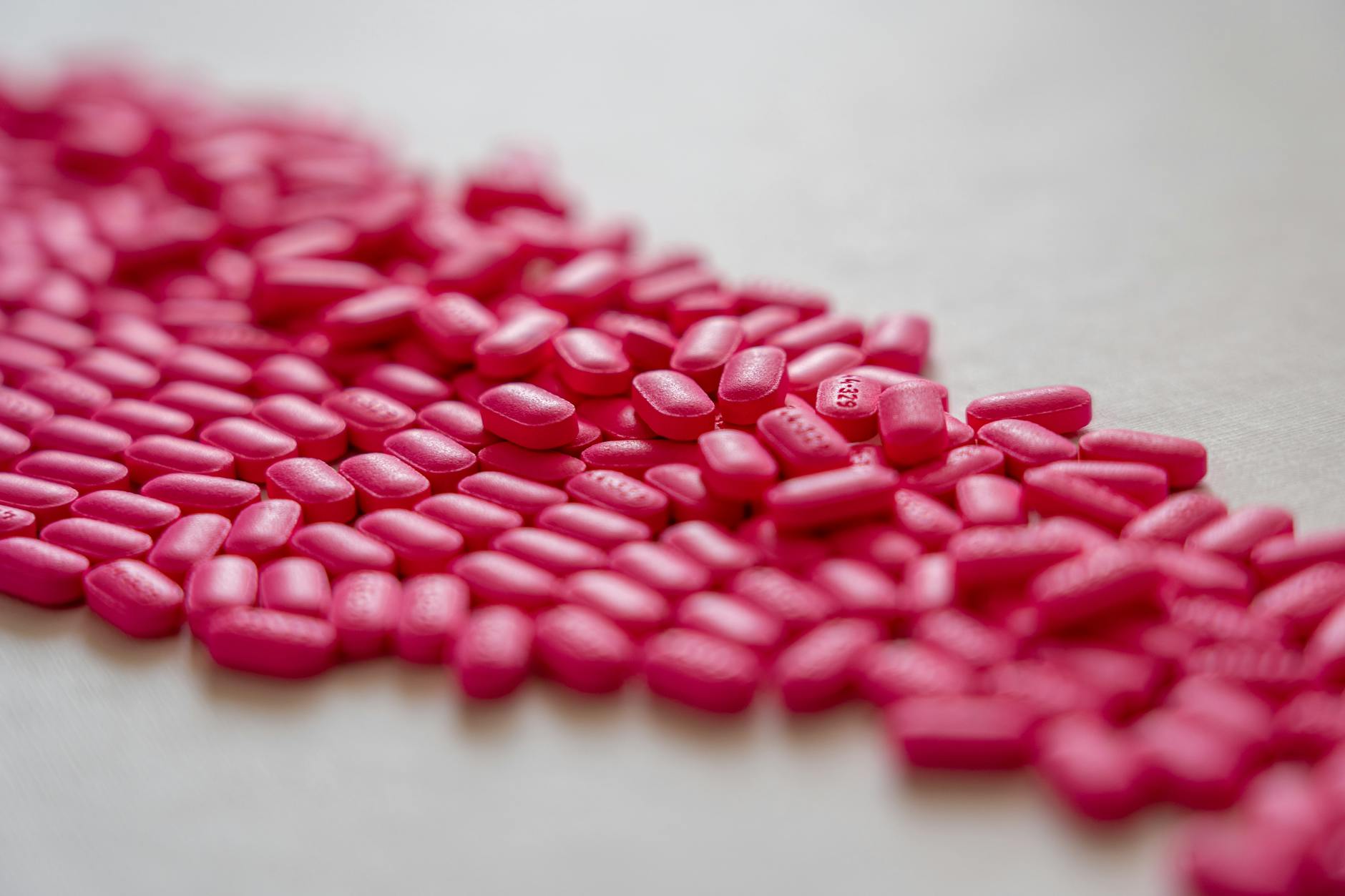A detailed array of pink pills on a white surface, ideal for health and pharmacy topics. - spring allergy irritability