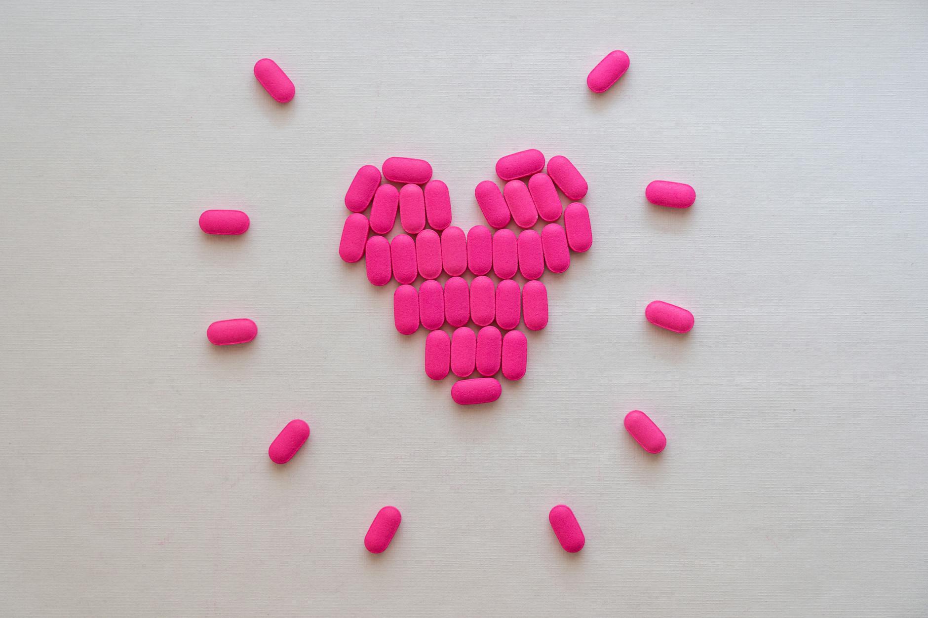 Pink pills arranged in a heart shape on a neutral surface. Perfect for health and medication themes. - spring allergy irritability