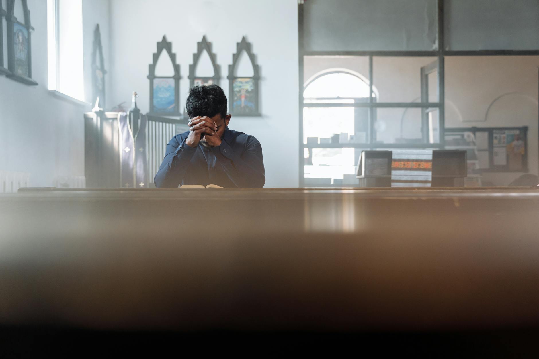 A man in prayer in a sunlit room, reflecting spirituality and peace. - spring anxiety relief