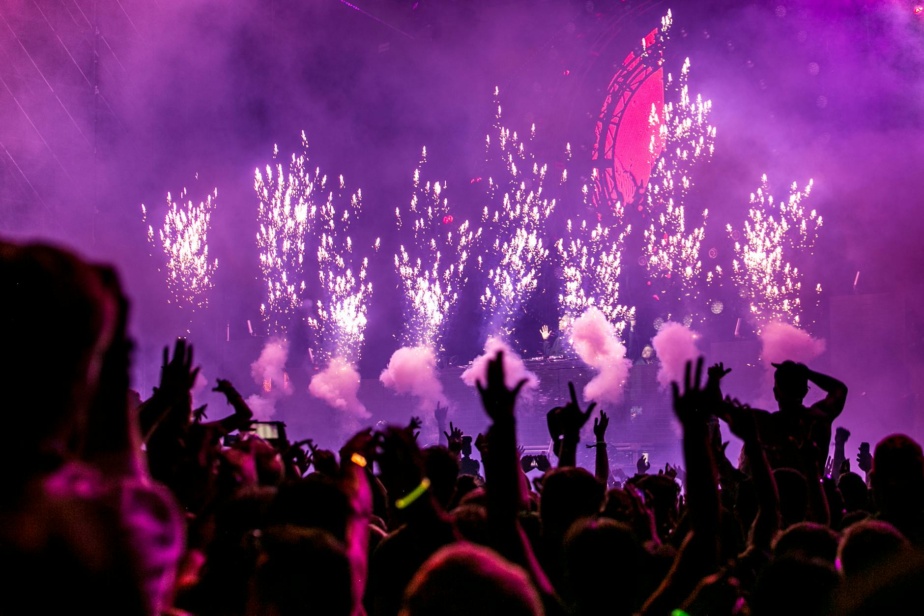 Vibrant EDM concert scene with fireworks, smoke, and enthusiastic crowd enjoying the music. - spring break kids
