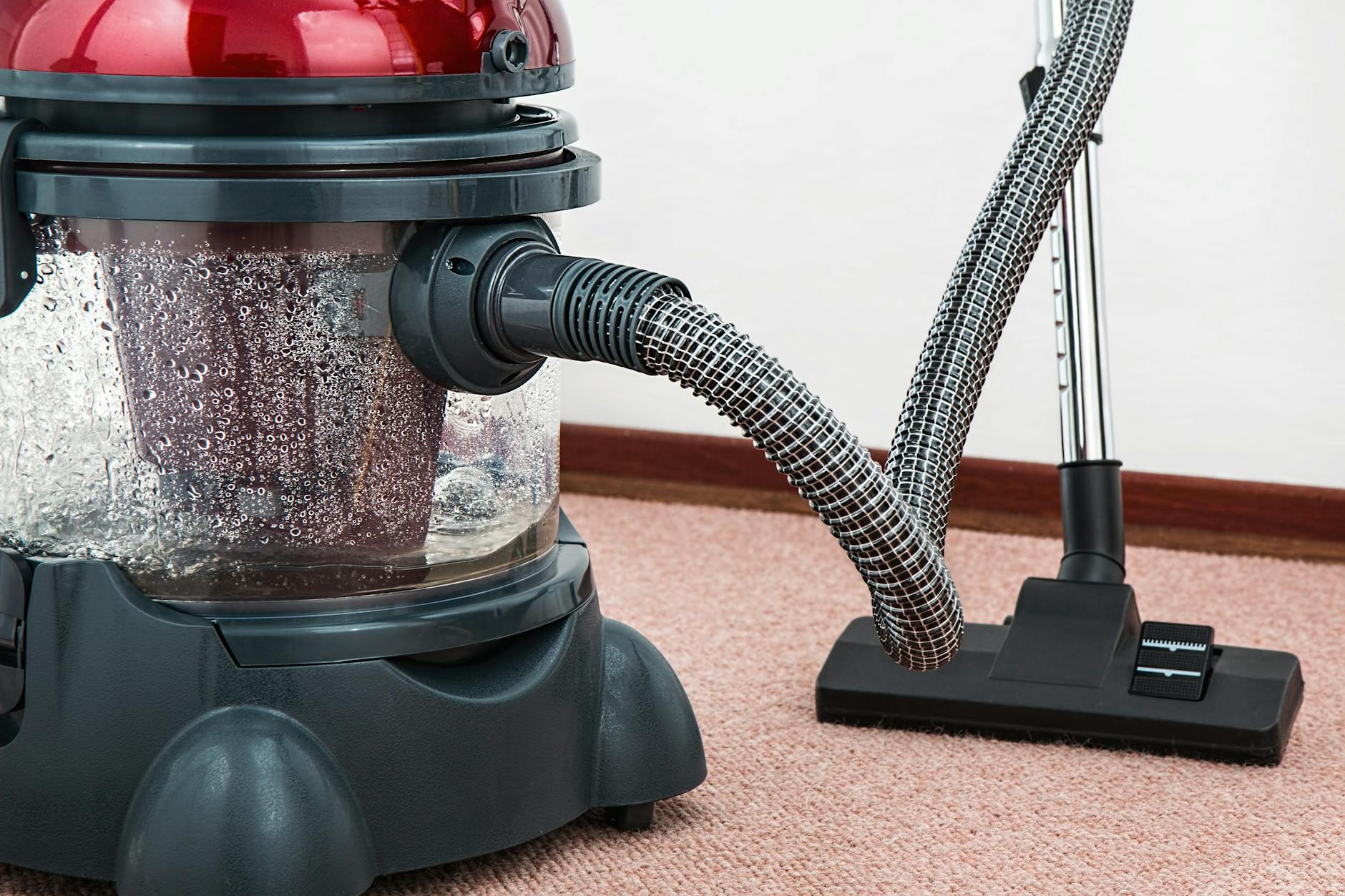Close-up of a modern vacuum cleaner with water filtration on carpet floor indoors. - spring chore division